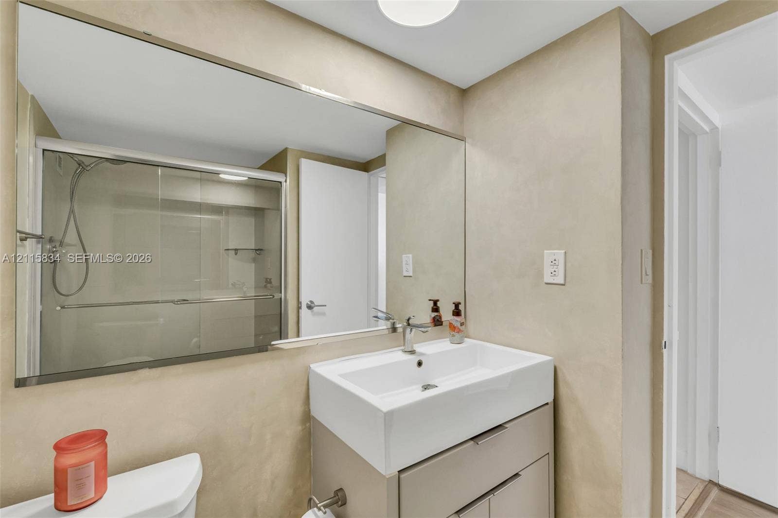 5161 Collins Avenue, #1717, Miami Beach, Miami Beach, FL 33140 Wall-to-wall vanity mirror, square vessel sink with single-lever chrome faucet, modern floating vanity cabinet with metal hardware, and glass-enclosed shower with adjustable handheld fixture