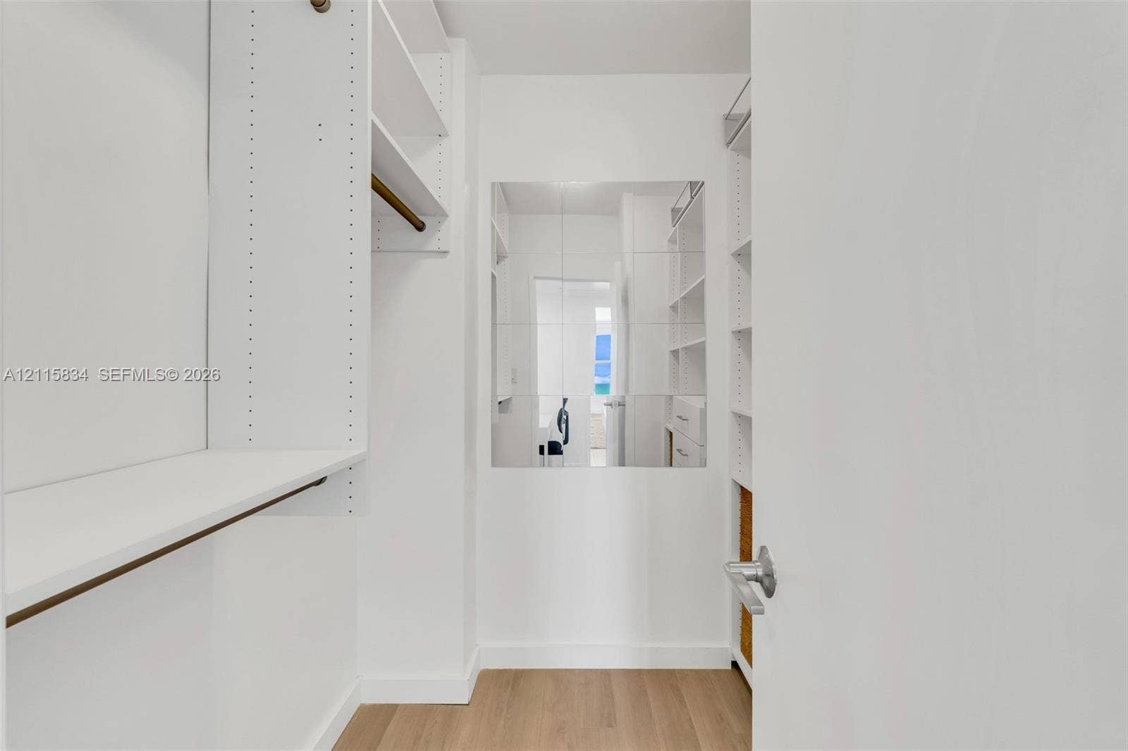 5161 Collins Avenue, #1717, Miami Beach, Miami Beach, FL 33140 Walk-in closet featuring white built-in shelving, integrated hanging rods, wall-mounted mirror, and wood-finish flooring