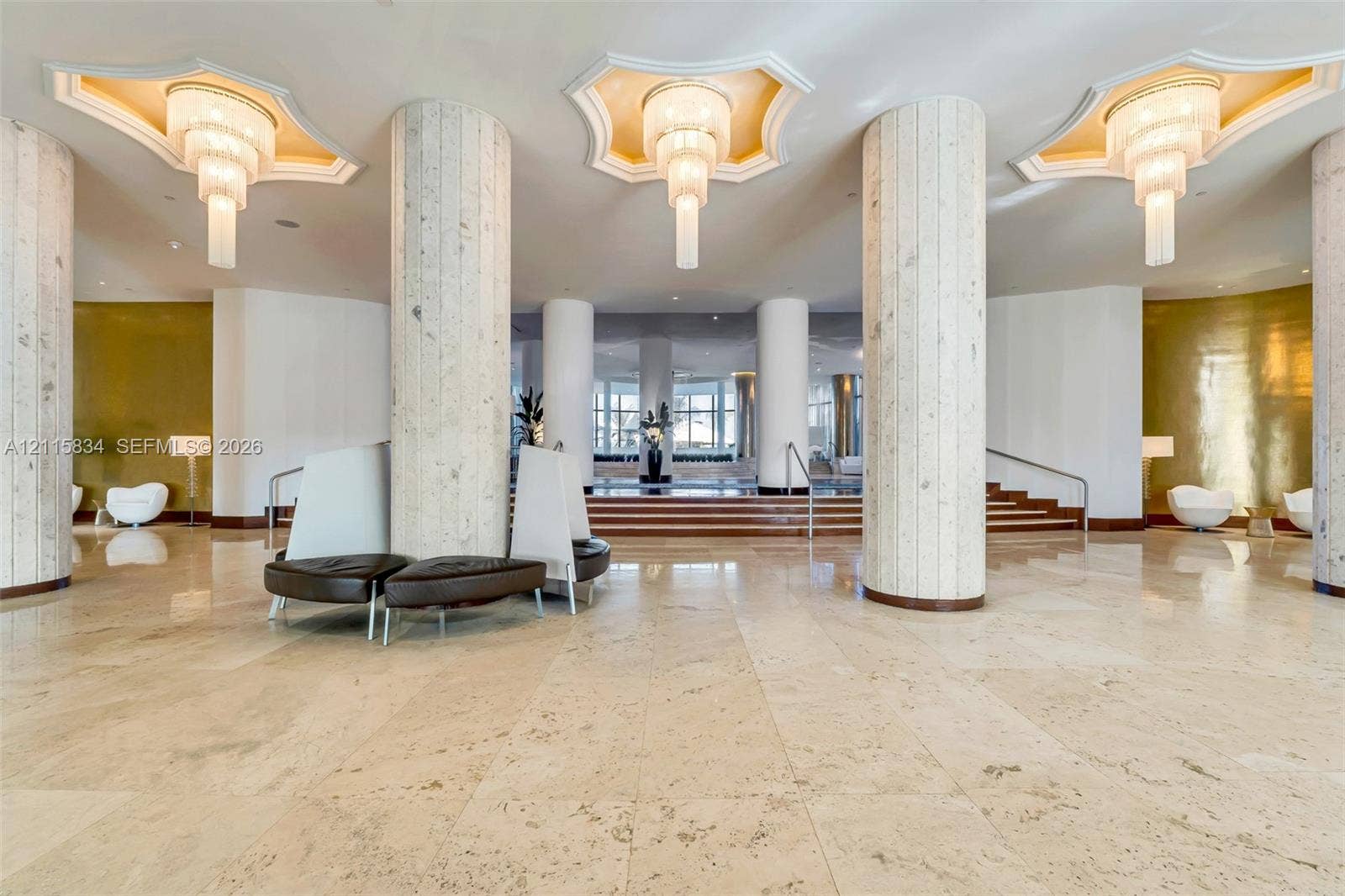 5161 Collins Avenue, #1717, Miami Beach, Miami Beach, FL 33140 Grand lobby featuring polished stone flooring, towering cylindrical structural columns, multi-tiered tiered tiered pendant lighting, recessed tray ceiling detailing, and metallic wall accents