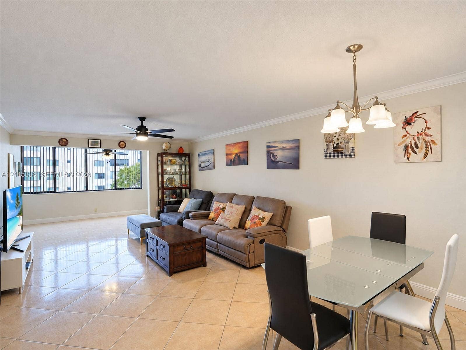 8000 Hampton Boulevard, #311, North Lauderdale, North Lauderdale, FL 33068 Open-concept area featuring light-toned tile flooring, crown molding, a multi-arm chandelier, and floor-to-ceiling windows with vertical blinds