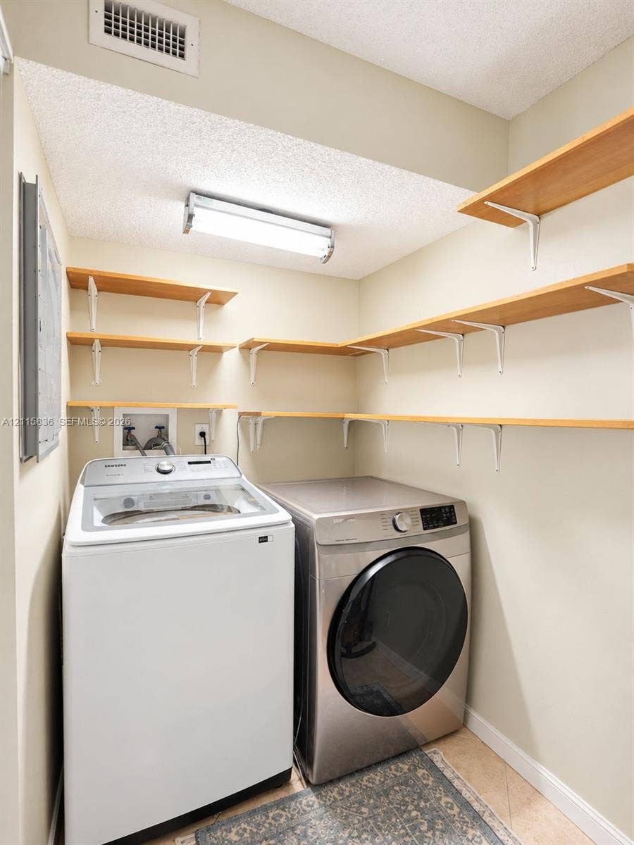 8000 Hampton Boulevard, #311, North Lauderdale, North Lauderdale, FL 33068 Utility area featuring stainless steel laundry appliances, multi-level wall-mounted shelving, and overhead linear lighting
