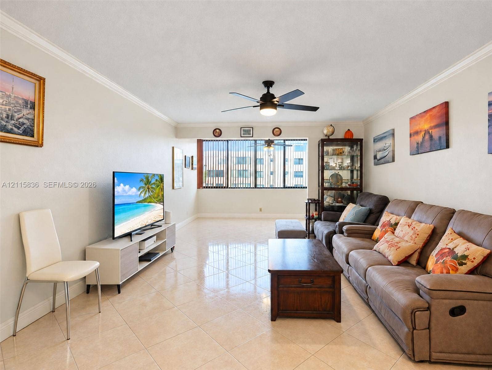 8000 Hampton Boulevard, #311, North Lauderdale, North Lauderdale, FL 33068 Neutral-toned room featuring large-format tile flooring, crown molding, a central ceiling fan with an integrated light fixture, and floor-to-ceiling windows