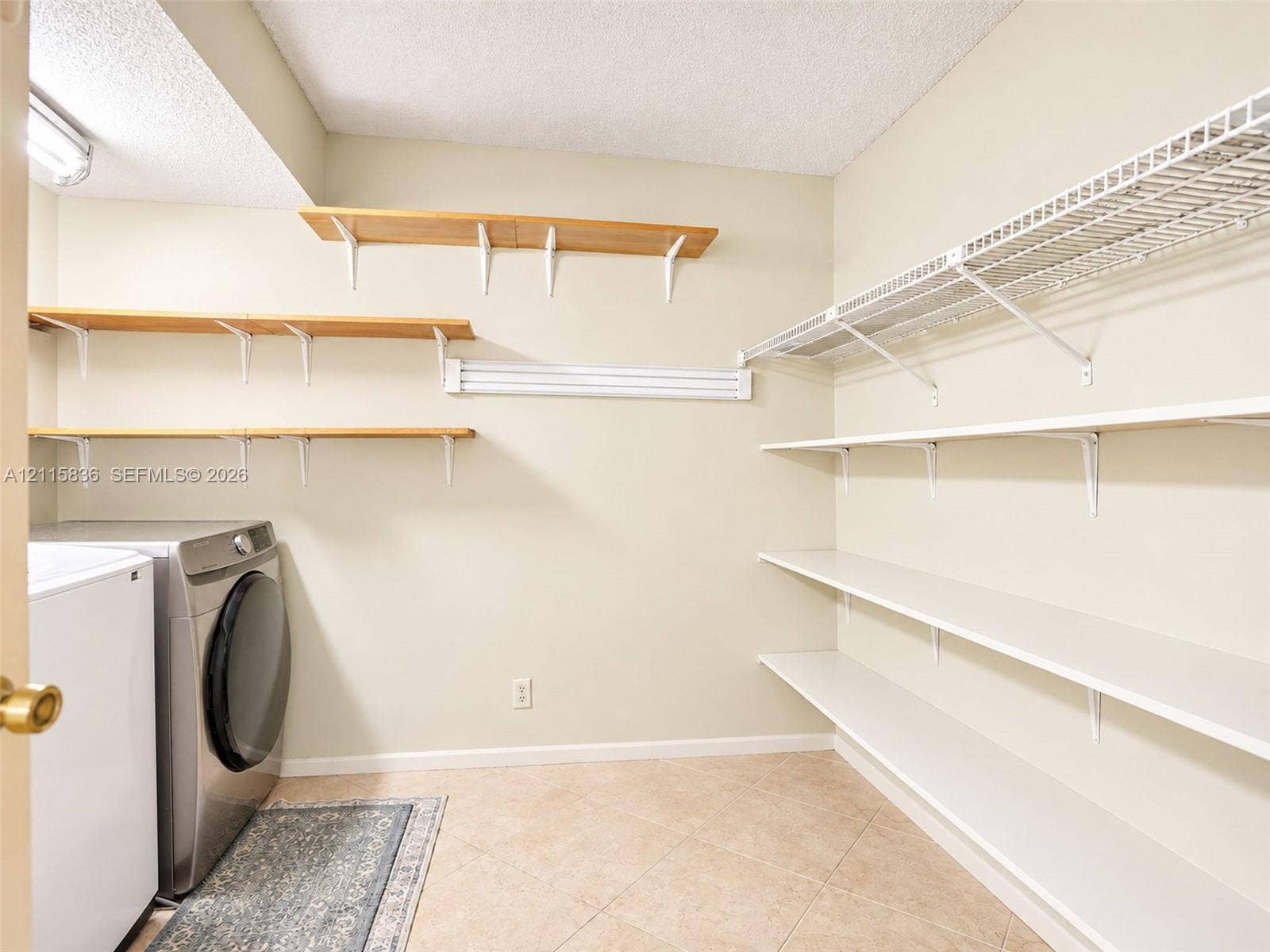 8000 Hampton Boulevard, #311, North Lauderdale, North Lauderdale, FL 33068 Laundry area featuring tile flooring, three tiers of natural wood-finish wall-mounted shelving, and tiered white wire shelving