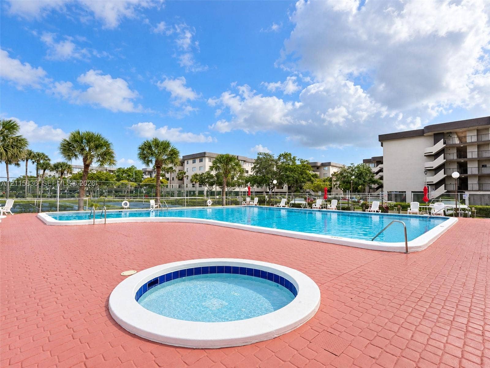 8000 Hampton Boulevard, #311, North Lauderdale, North Lauderdale, FL 33068 In-ground swimming pool and circular spa with surrounding paver patio, accented by mature palm trees and perimeter fencing
