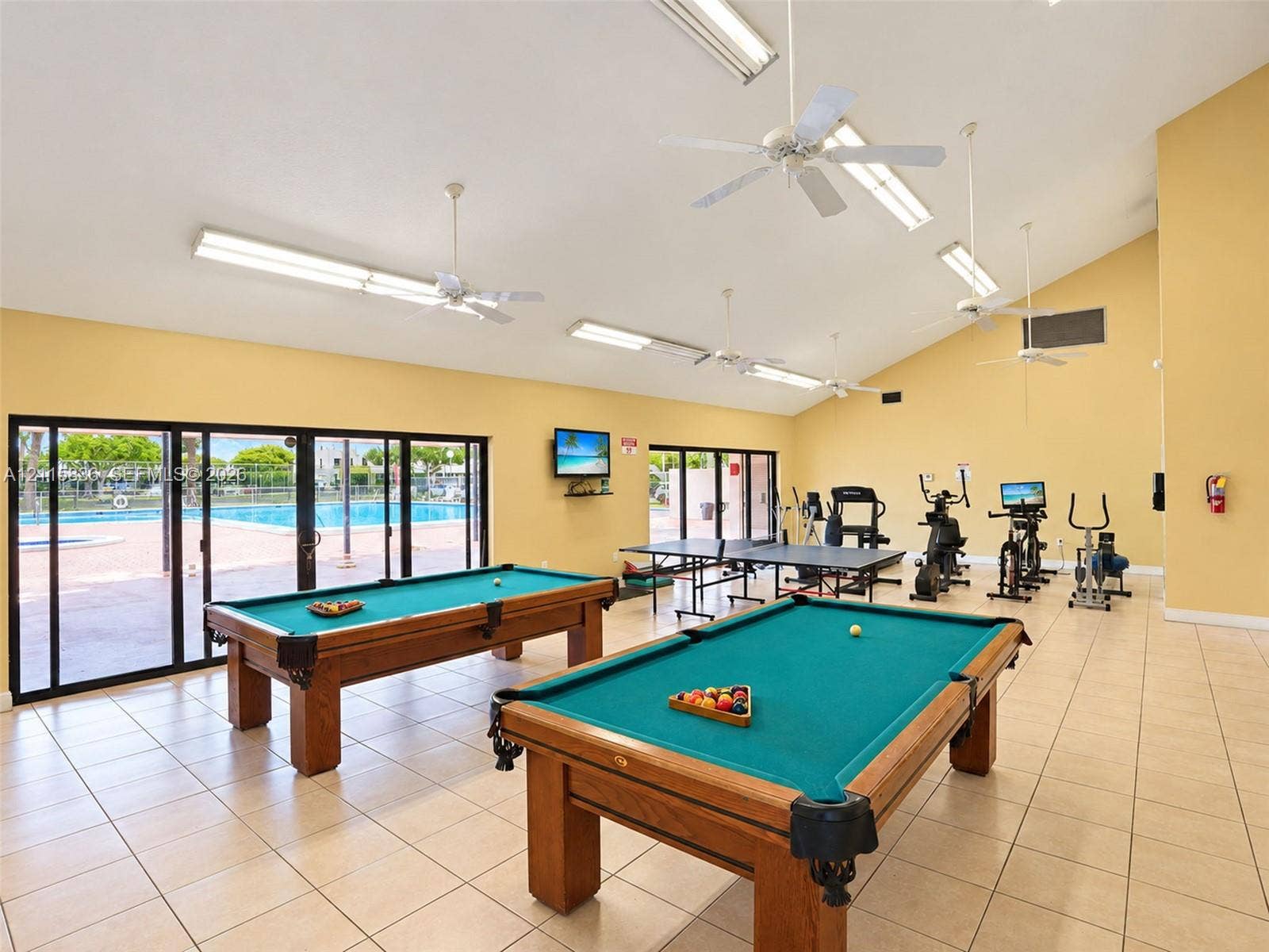 8000 Hampton Boulevard, #311, North Lauderdale, North Lauderdale, FL 33068 Recreational area featuring ceramic tile flooring, vaulted ceilings with mounted ceiling fans, and expansive sliding glass doors providing outdoor access