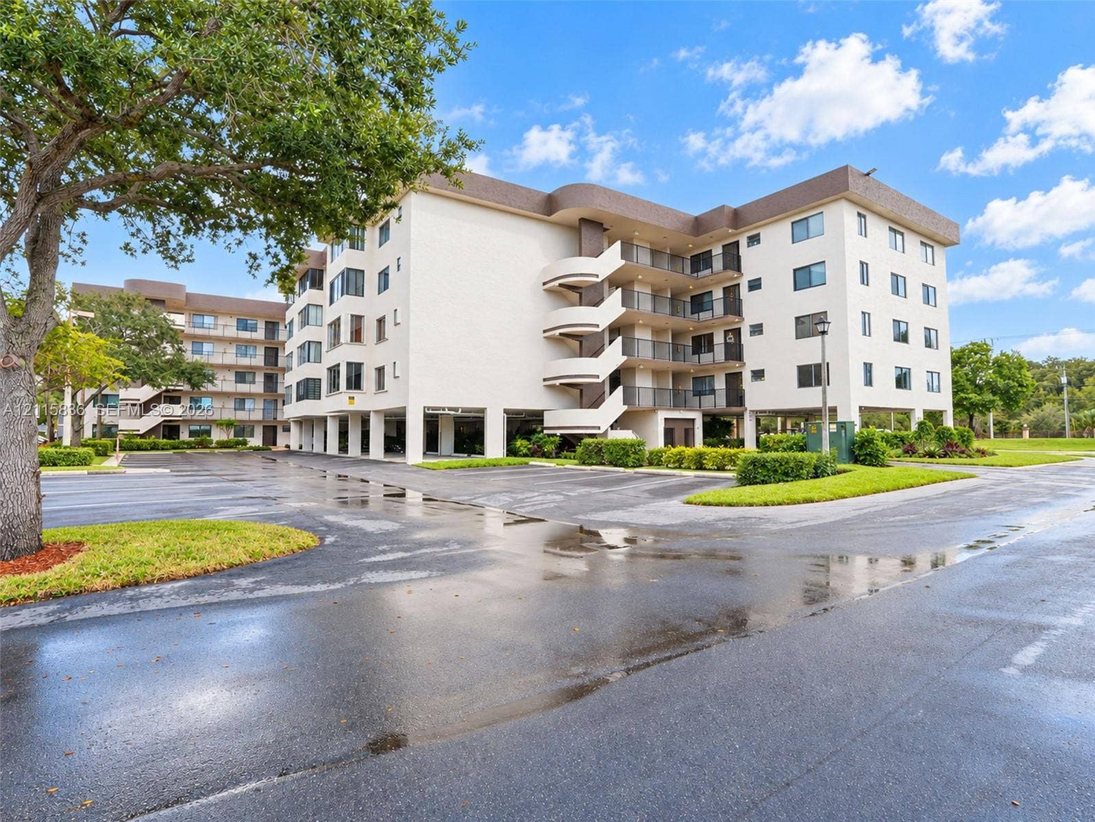 8000 Hampton Boulevard, #311, North Lauderdale, North Lauderdale, FL 33068 Multi-story building exterior featuring smooth stucco finish, cantilevered stairwell structures, metal balcony railings, and covered ground-level parking