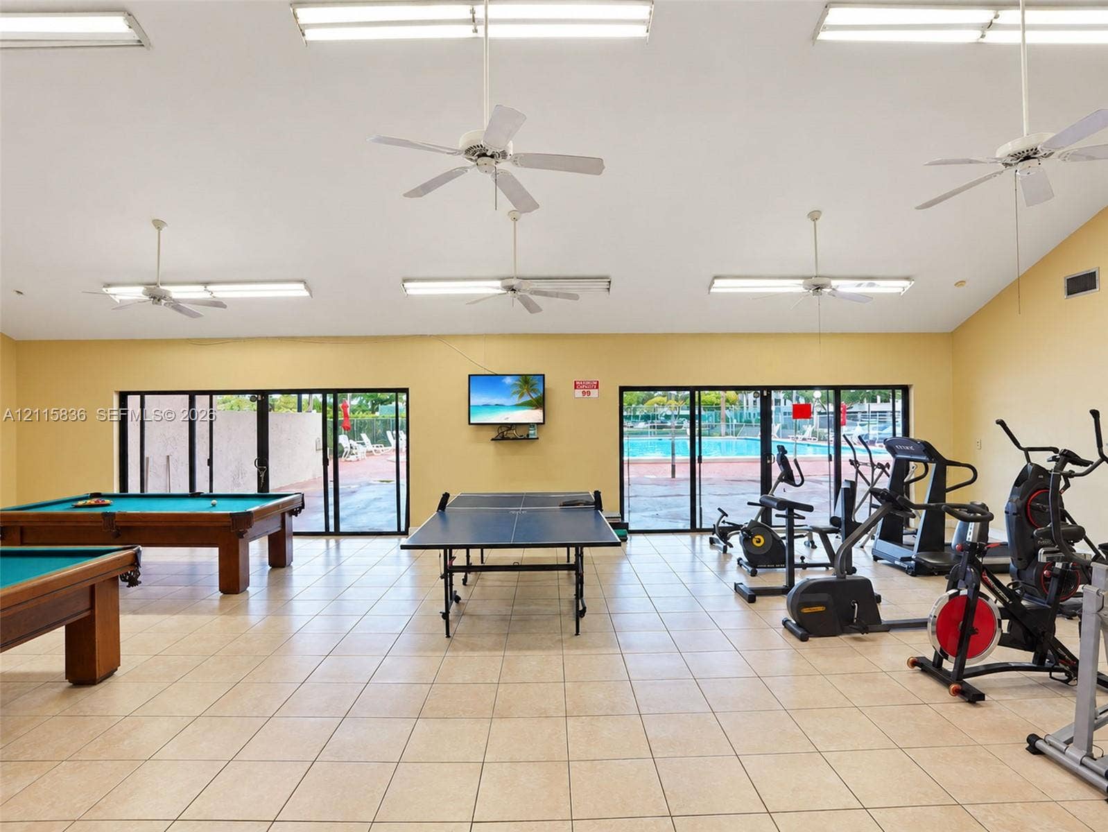 8000 Hampton Boulevard, #311, North Lauderdale, North Lauderdale, FL 33068 Multi-purpose recreation room featuring ceramic tile flooring, vaulted ceilings with integrated ceiling fans, and floor-to-ceiling glass sliding doors