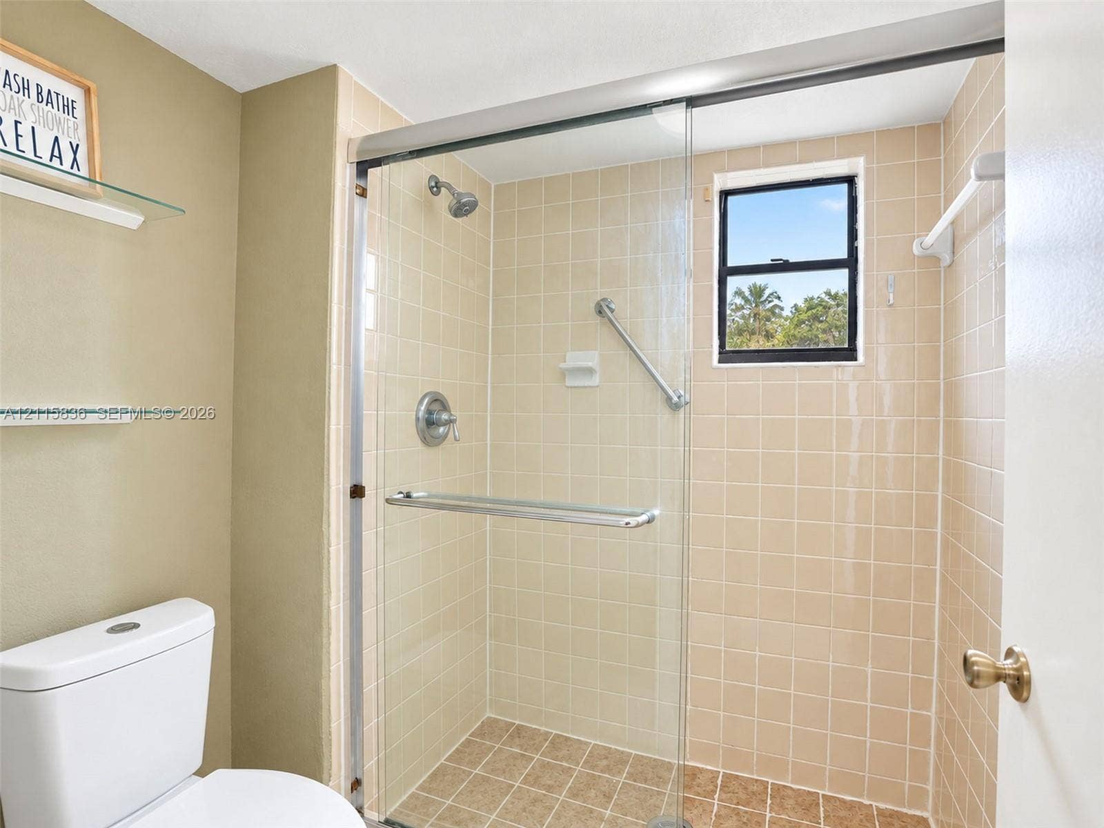 8000 Hampton Boulevard, #311, North Lauderdale, North Lauderdale, FL 33068 Walk-in shower featuring a sliding glass enclosure, ceramic tile surround, integrated grab bar, and wall-mounted showerhead, accompanied by two built-in glass shelving units