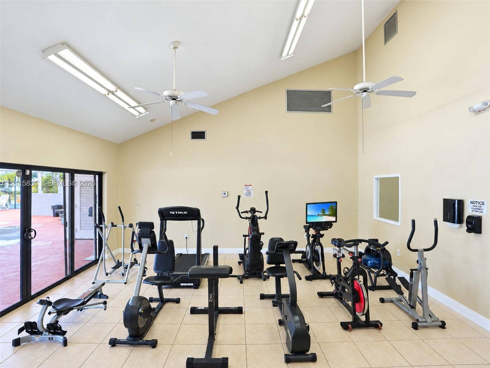 8000 Hampton Boulevard, #311, North Lauderdale, North Lauderdale, FL 33068 Vaulted ceiling with dual overhead ceiling fans, linear fluorescent lighting, tile flooring, and sliding glass door access