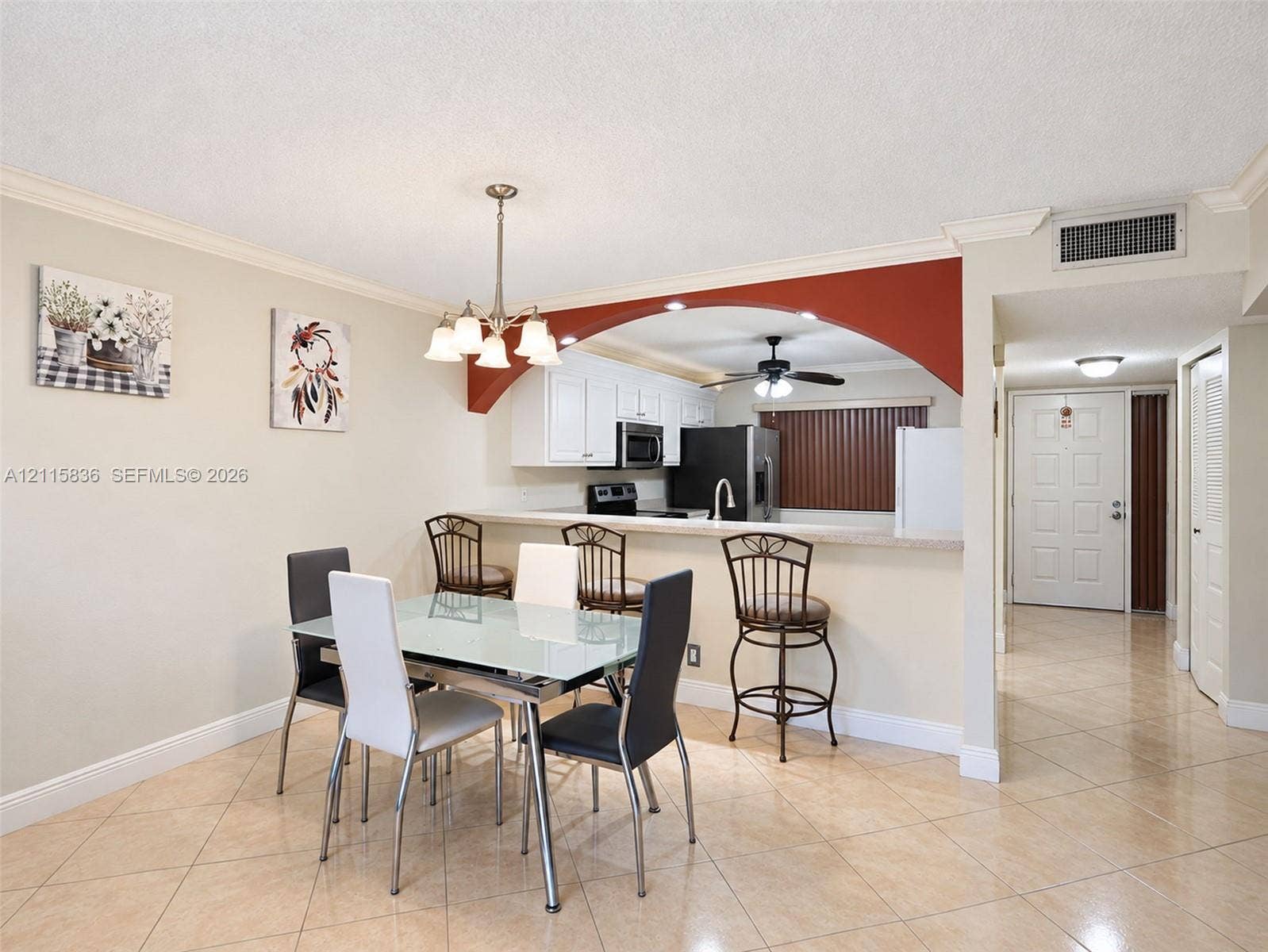8000 Hampton Boulevard, #311, North Lauderdale, North Lauderdale, FL 33068 Dining area featuring tile flooring, a decorative chandelier, and a kitchen pass-through with a built-in breakfast bar framed by a rounded archway