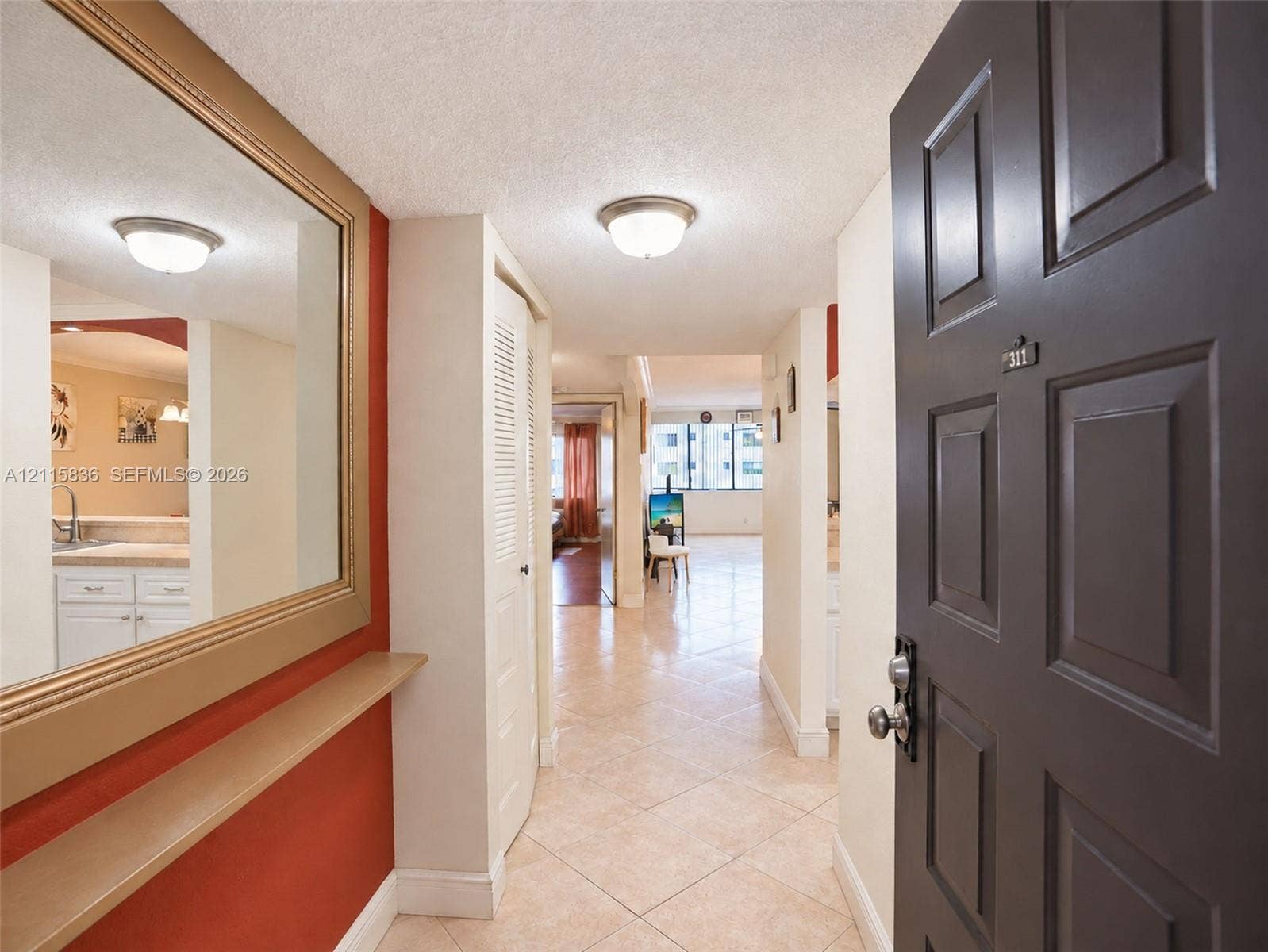 8000 Hampton Boulevard, #311, North Lauderdale, North Lauderdale, FL 33068 Entryway featuring large wall-mounted mirror, built-in shelving, tiled flooring, louvered closet doors, and flush-mount ceiling lighting