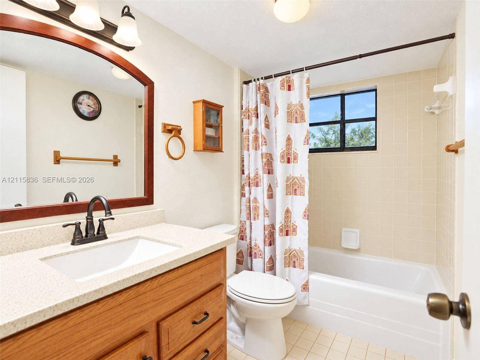 8000 Hampton Boulevard, #311, North Lauderdale, North Lauderdale, FL 33068 Bathroom featuring a wood-tone vanity, light-colored stone-finish countertop with an undermount sink, oil-rubbed bronze fixtures, arched wall-mounted mirror, and a tiled tub-shower combination with a window