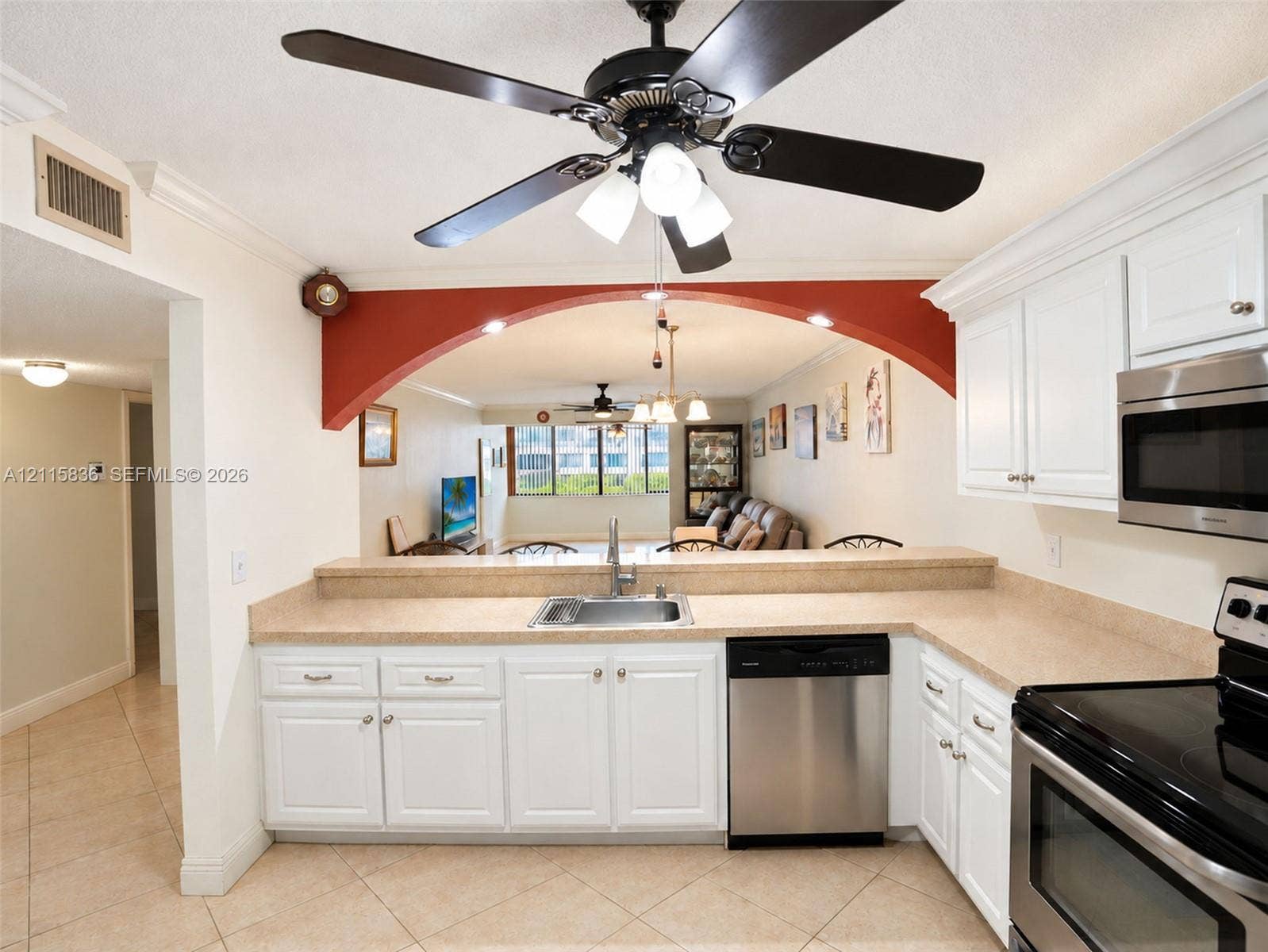 8000 Hampton Boulevard, #311, North Lauderdale, North Lauderdale, FL 33068 Kitchen featuring white cabinetry, solid-surface countertops, stainless steel appliances, tile flooring, and a decorative arched pass-through opening