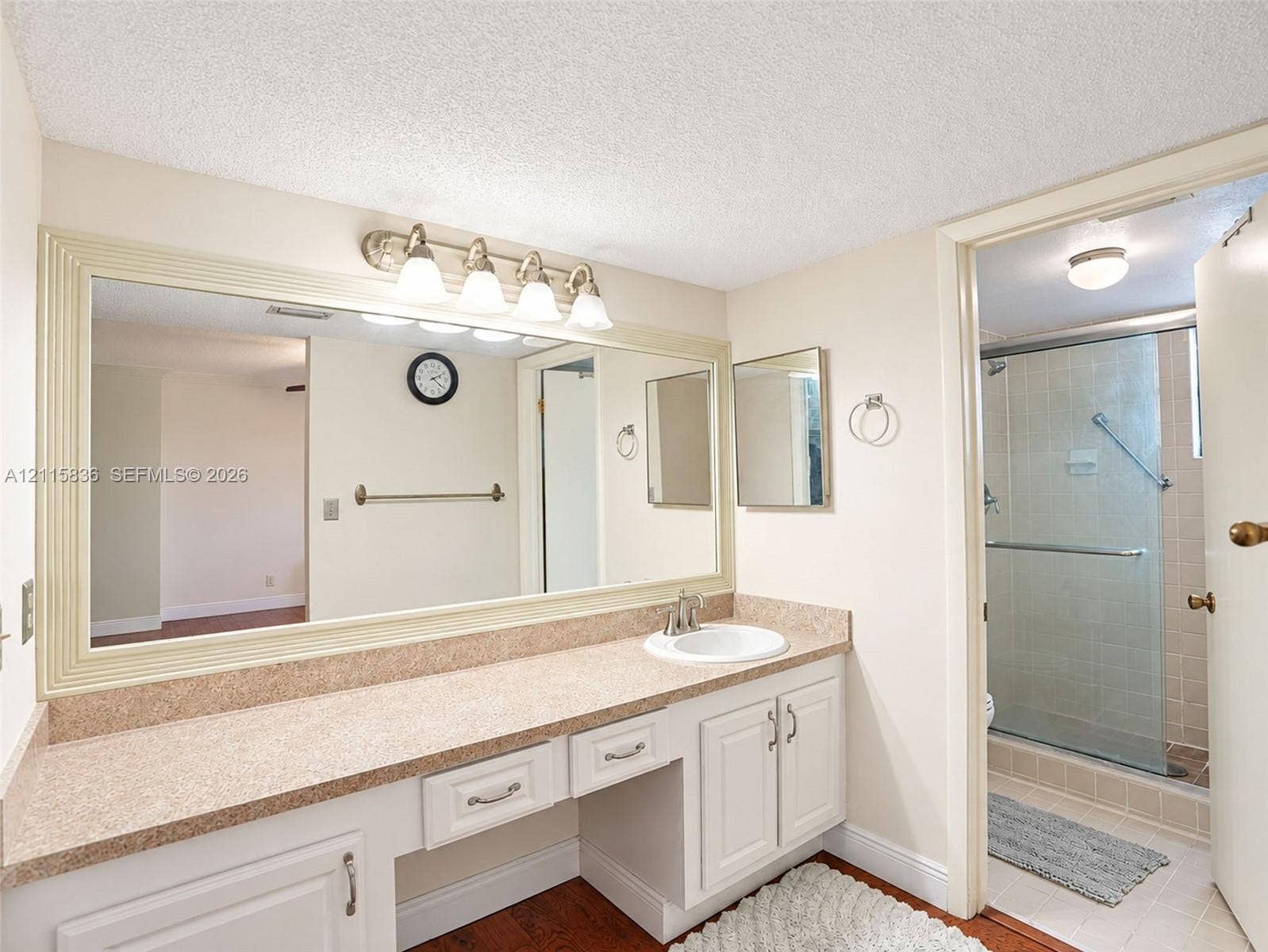 8000 Hampton Boulevard, #311, North Lauderdale, North Lauderdale, FL 33068 Bathroom featuring a dual-section vanity with a stone-composite countertop, integrated sink, oversized framed mirror, and a walk-in shower enclosure with a glass door