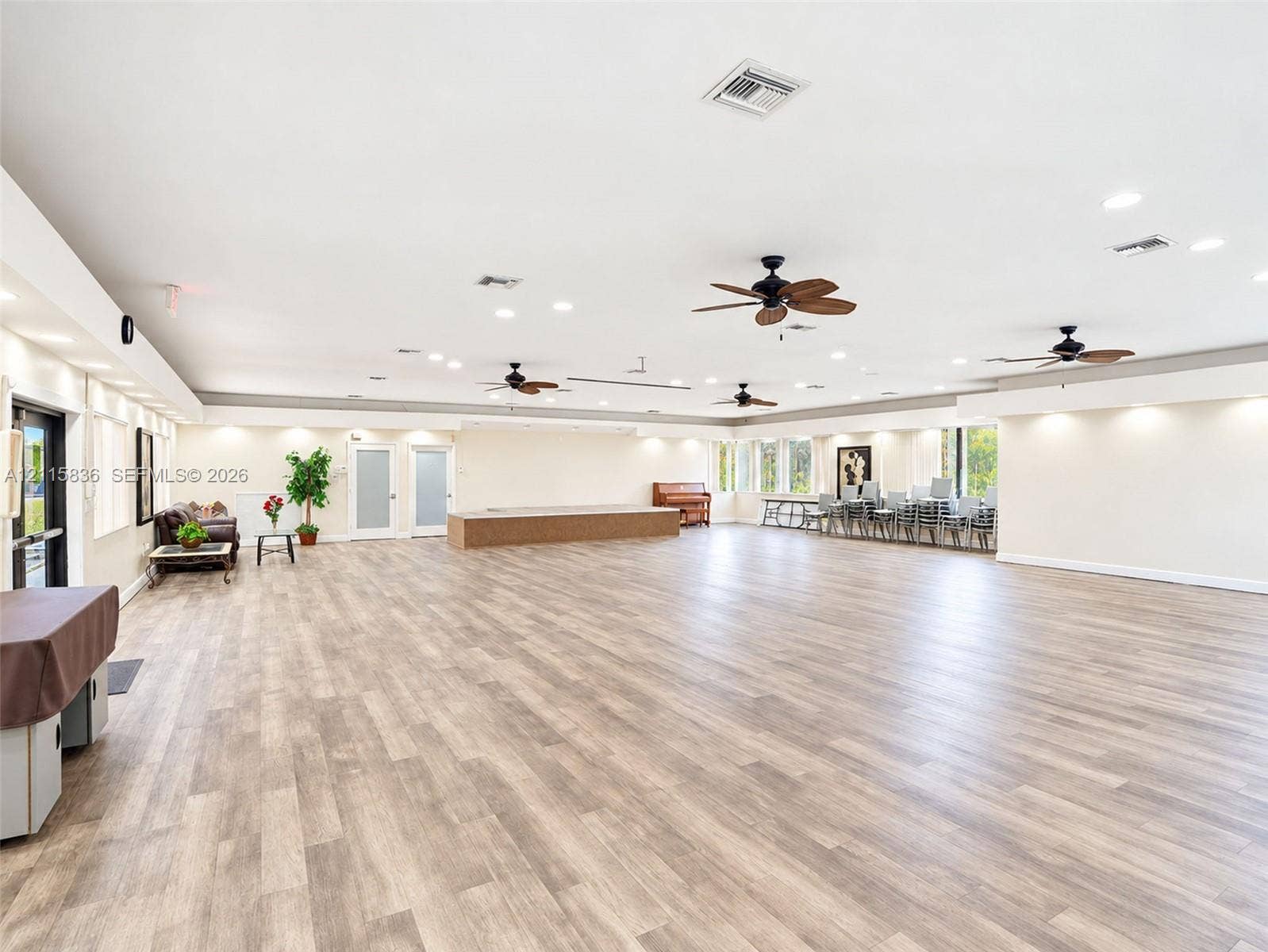 8000 Hampton Boulevard, #311, North Lauderdale, North Lauderdale, FL 33068 Expansive open-concept interior featuring wood-finish flooring, recessed lighting, multiple ceiling fans, and a raised wooden platform stage