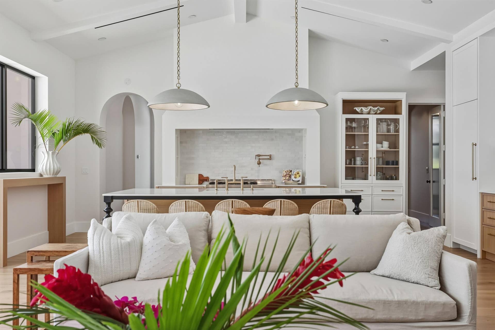 Oversized range hood with Visual Comfort pendants over an oversized marble kitchen island