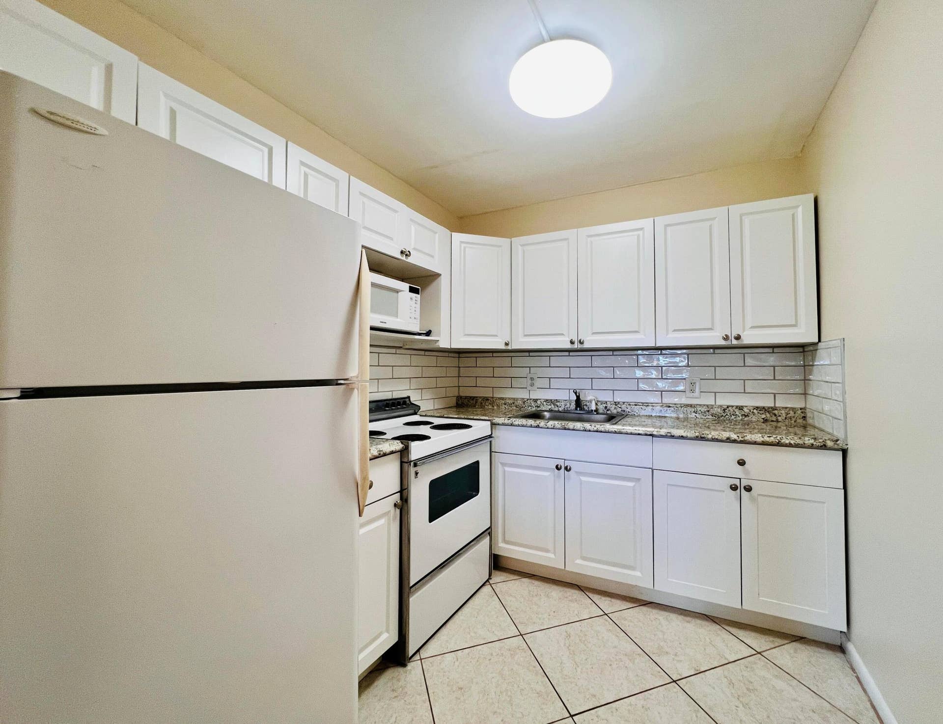 27 Sheffield B, West Palm Beach, FL 33417 Pretty Updated Kitchen Featuring Crisp White Cabinets, Grante Look Counters, and Modern Subway Tile Backsplash