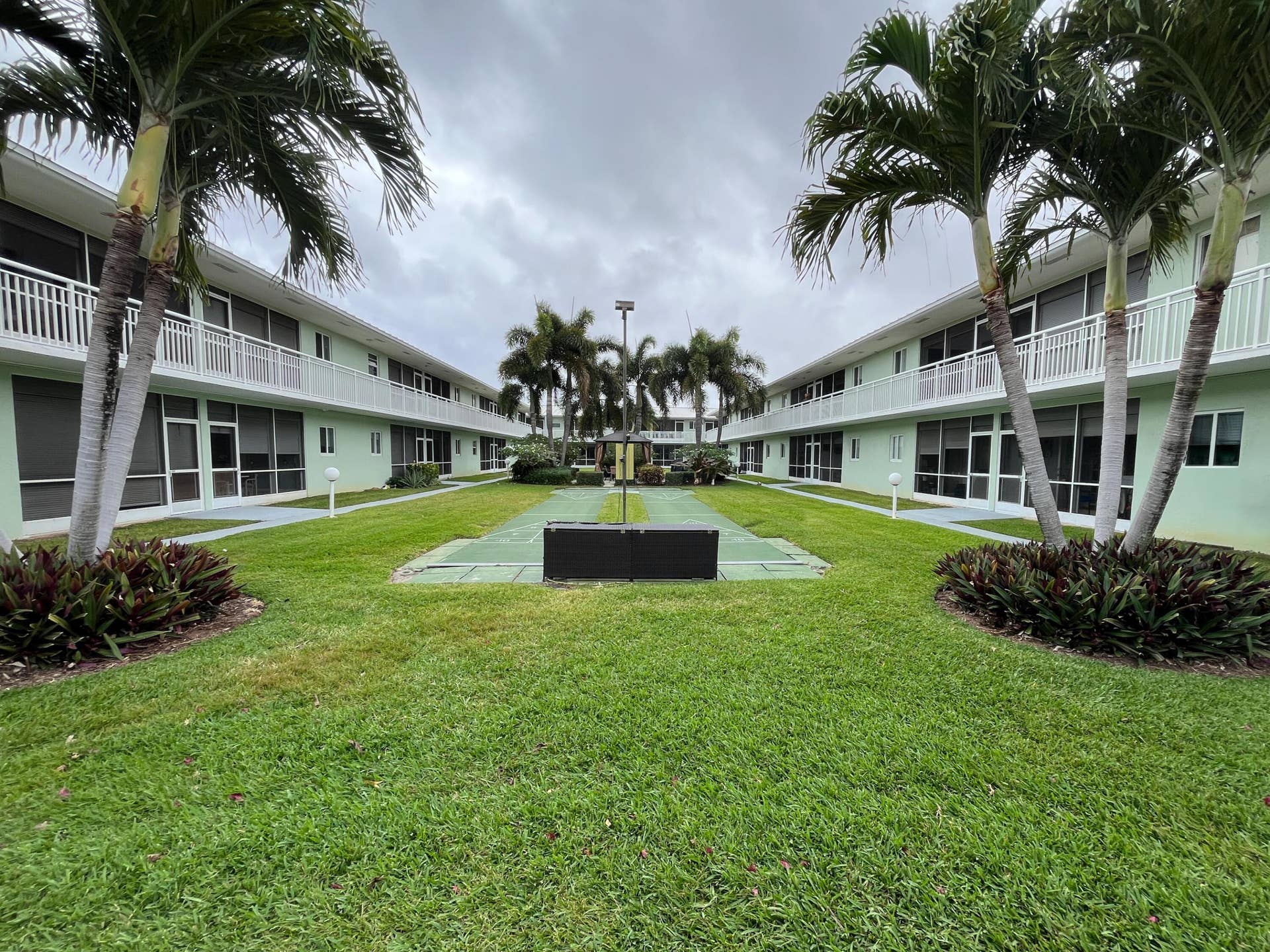 Another view of the courtyard which includes the heated pool, shuffleboard, grill and shaded sitting areas.