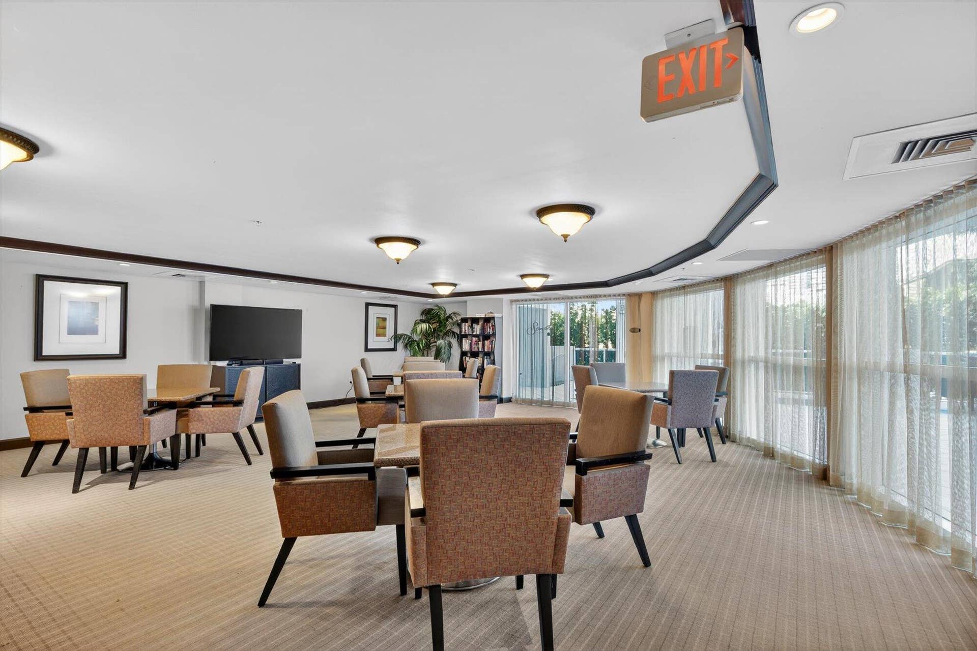 801 Briny Avenue, #1501, Pompano Beach, FL 33062 Light-filled community room with tables, TV, and charming library nook