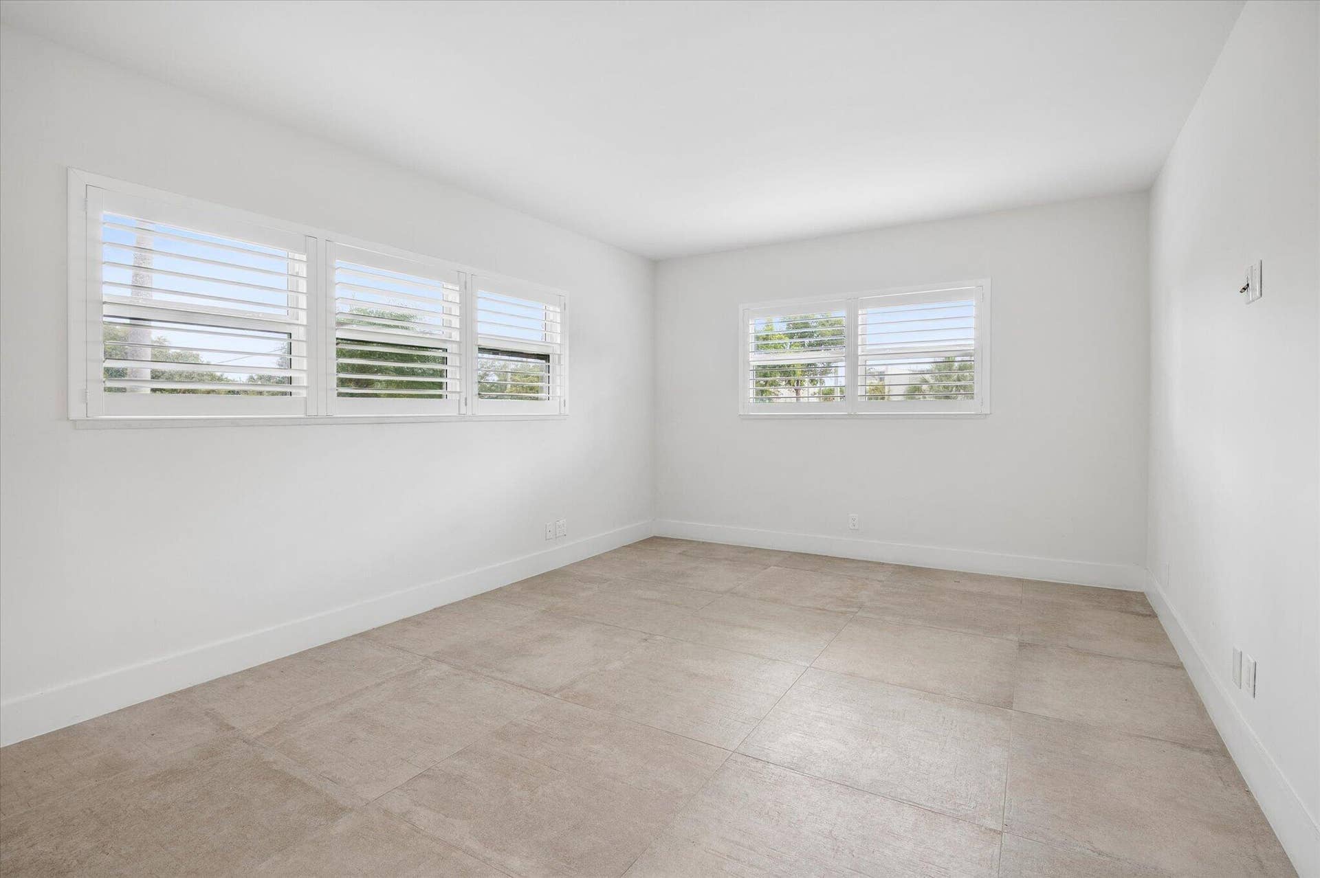 5100 Bayview Drive, #106, Fort Lauderdale, FL 33308 Bright and comfortable primary ensuite bedroom with clean white plantation shutters for privacy.