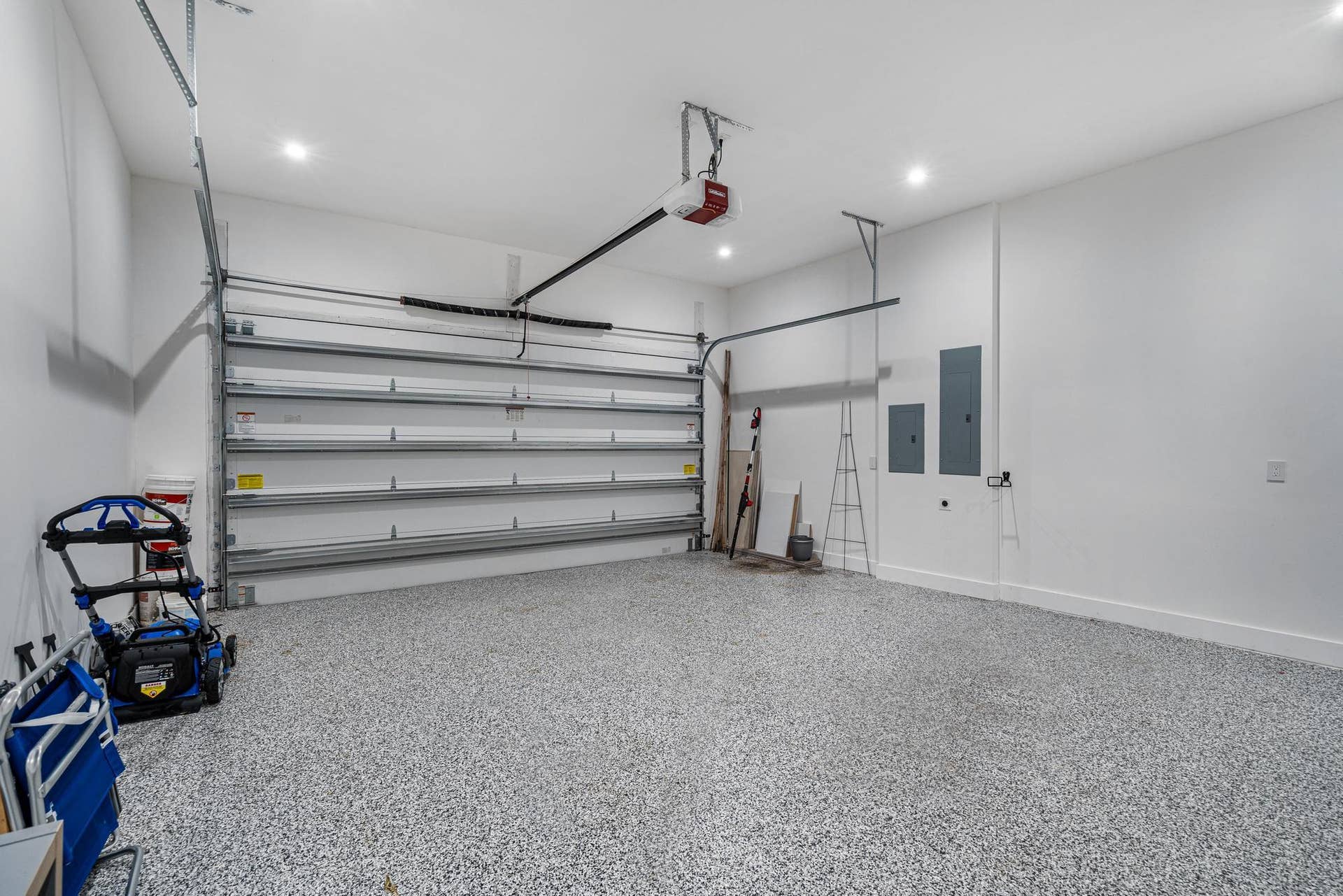 Two-car garage featuring decorative flake flooring and integrated EV charging.