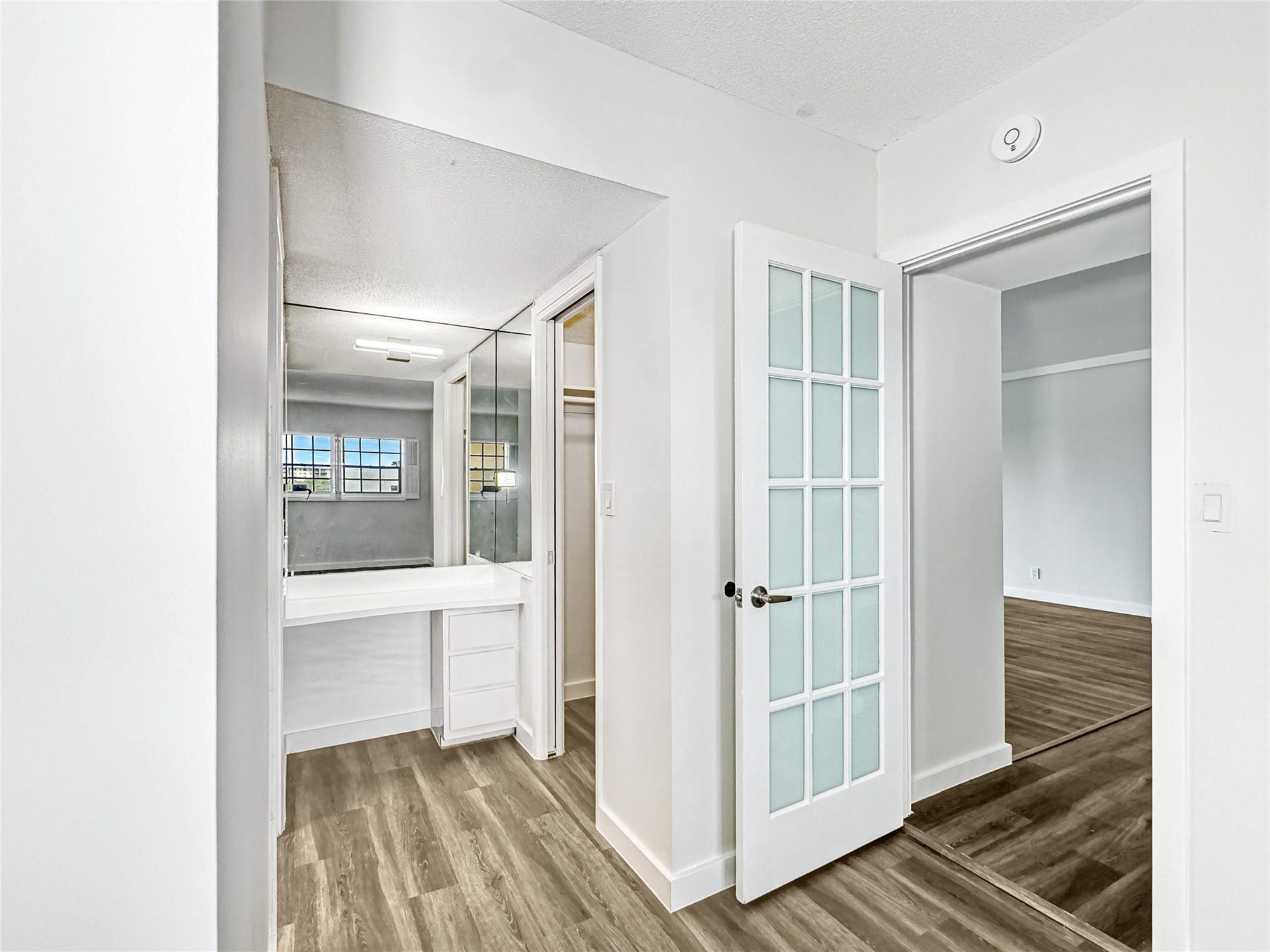 2950 N Palm Aire Drive, #506, Pompano Beach, FL 33069 Dressing area includes mirrored accents, built-in vanity space, and direct access to the bedroom. Vinyl flooring and neutral finishes create a clean, cohesive look throughout.