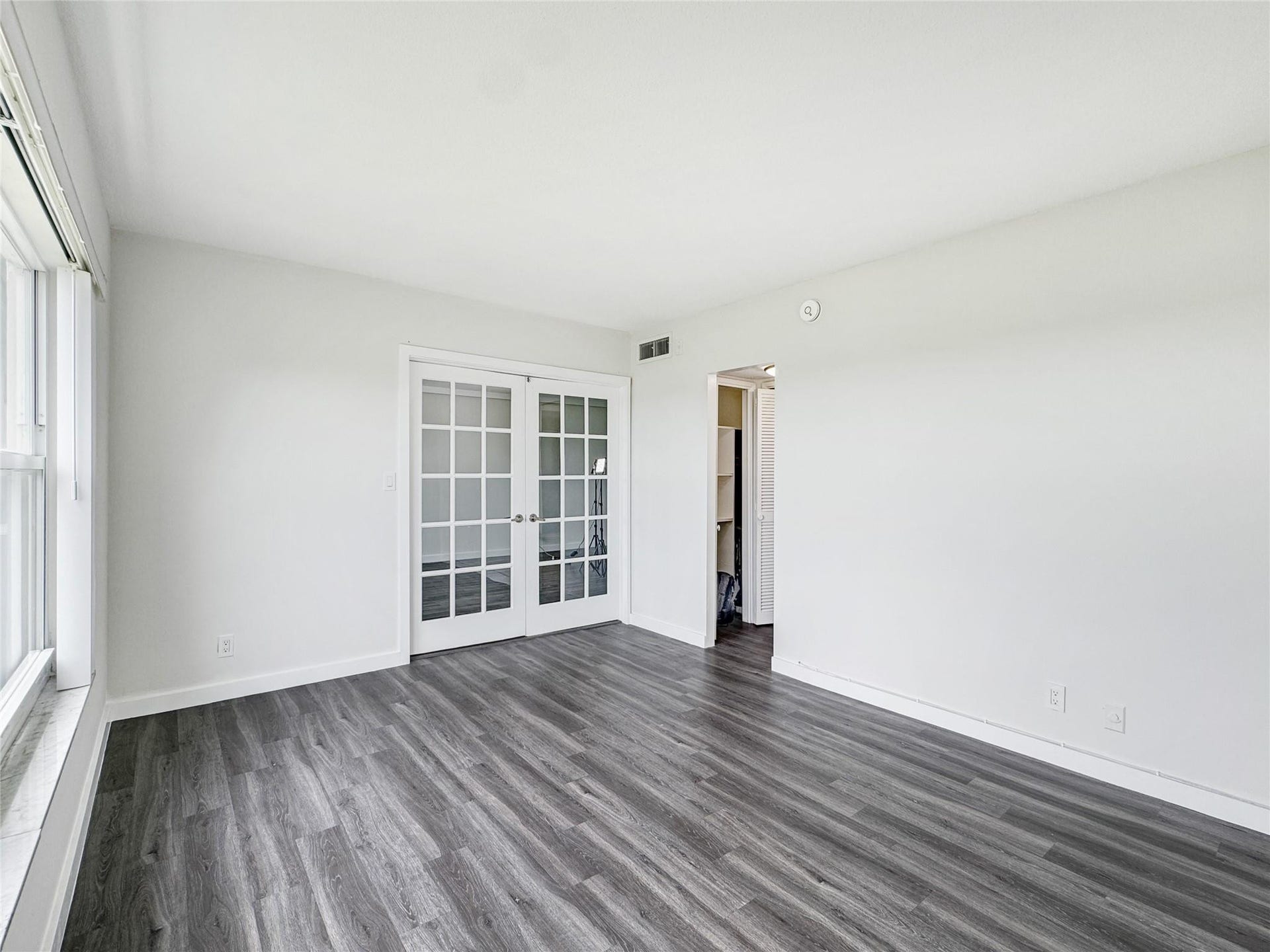 2950 N Palm Aire Drive, #506, Pompano Beach, FL 33069 Second Bedroom includes French doors connecting to the main living area and an en-suite bathroom, creating an ideal setup for guests, a home office, or additional lounge space. Neutral finishes and vinyl flooring maintain a clean, modern feel.