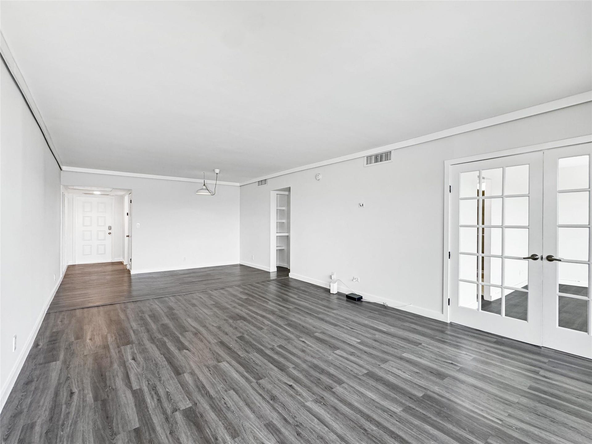 2950 N Palm Aire Drive, #506, Pompano Beach, FL 33069 Living room offers an expansive layout with neutral finishes, vinyl flooring, and direct access to the adjoining flex space through French doors. Open sightlines create a bright and airy feel throughout.