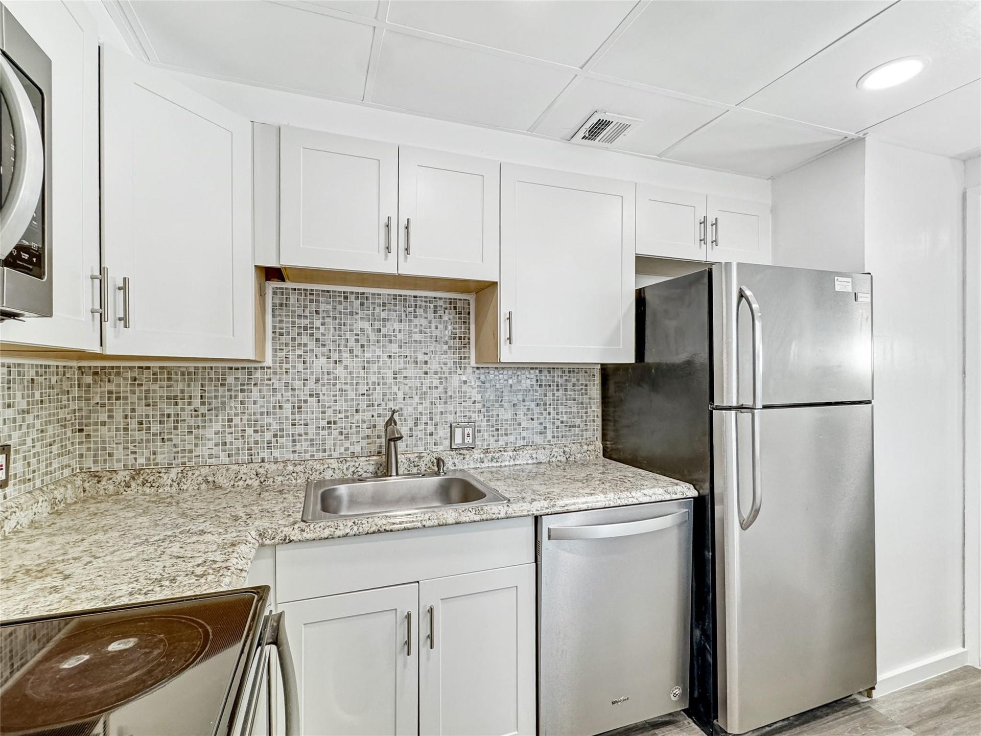 2950 N Palm Aire Drive, #506, Pompano Beach, FL 33069 Updated kitchen showcases granite-style countertops, mosaic tile backsplash, stainless steel appliances, and generous cabinet storage. Neutral finishes provide a bright and modern feel.