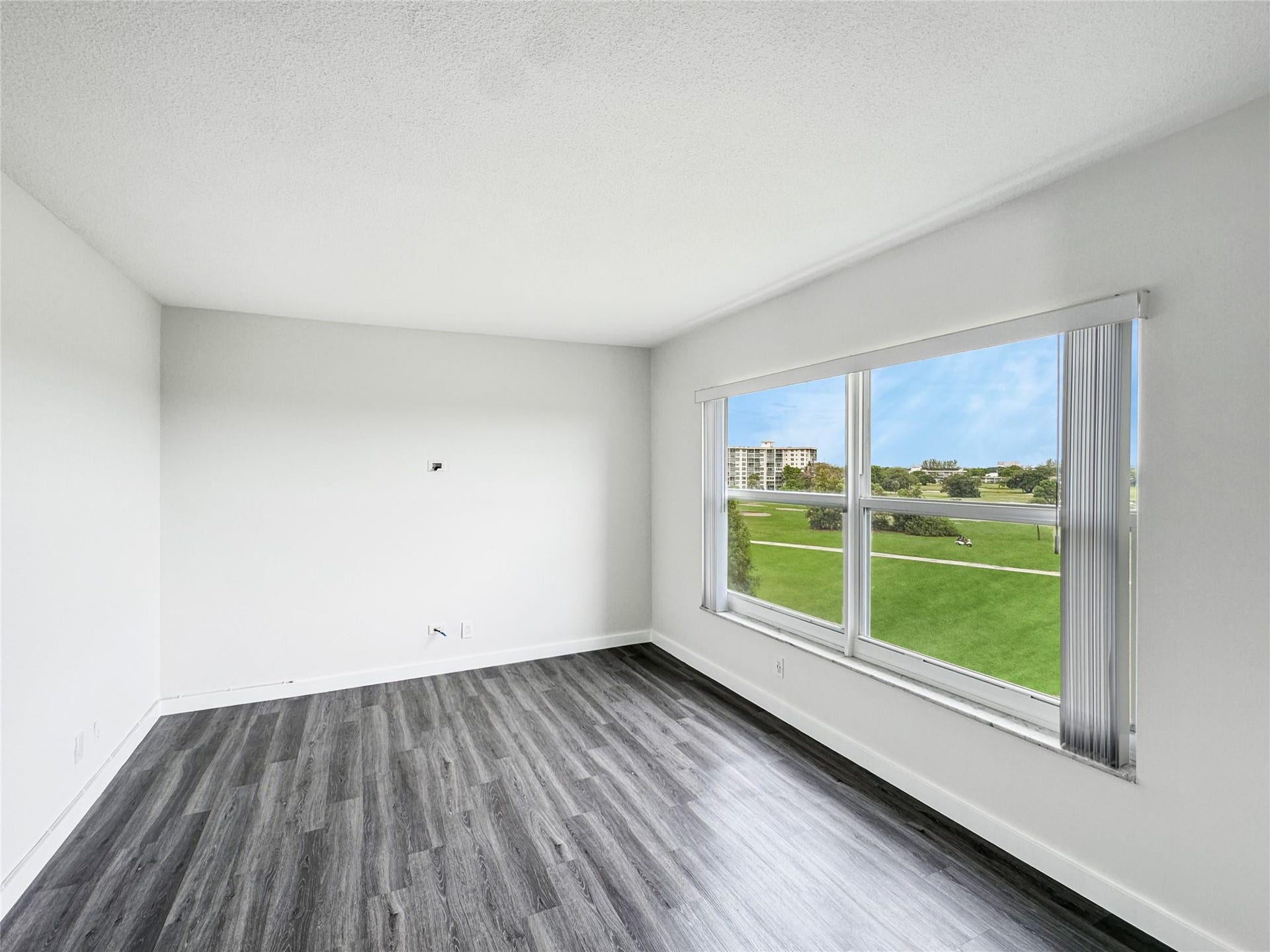 2950 N Palm Aire Drive, #506, Pompano Beach, FL 33069 Versatile second bedroom flex space features updated flooring, oversized windows, and peaceful green views, offering an ideal setup for a home office, reading room, or additional living area.