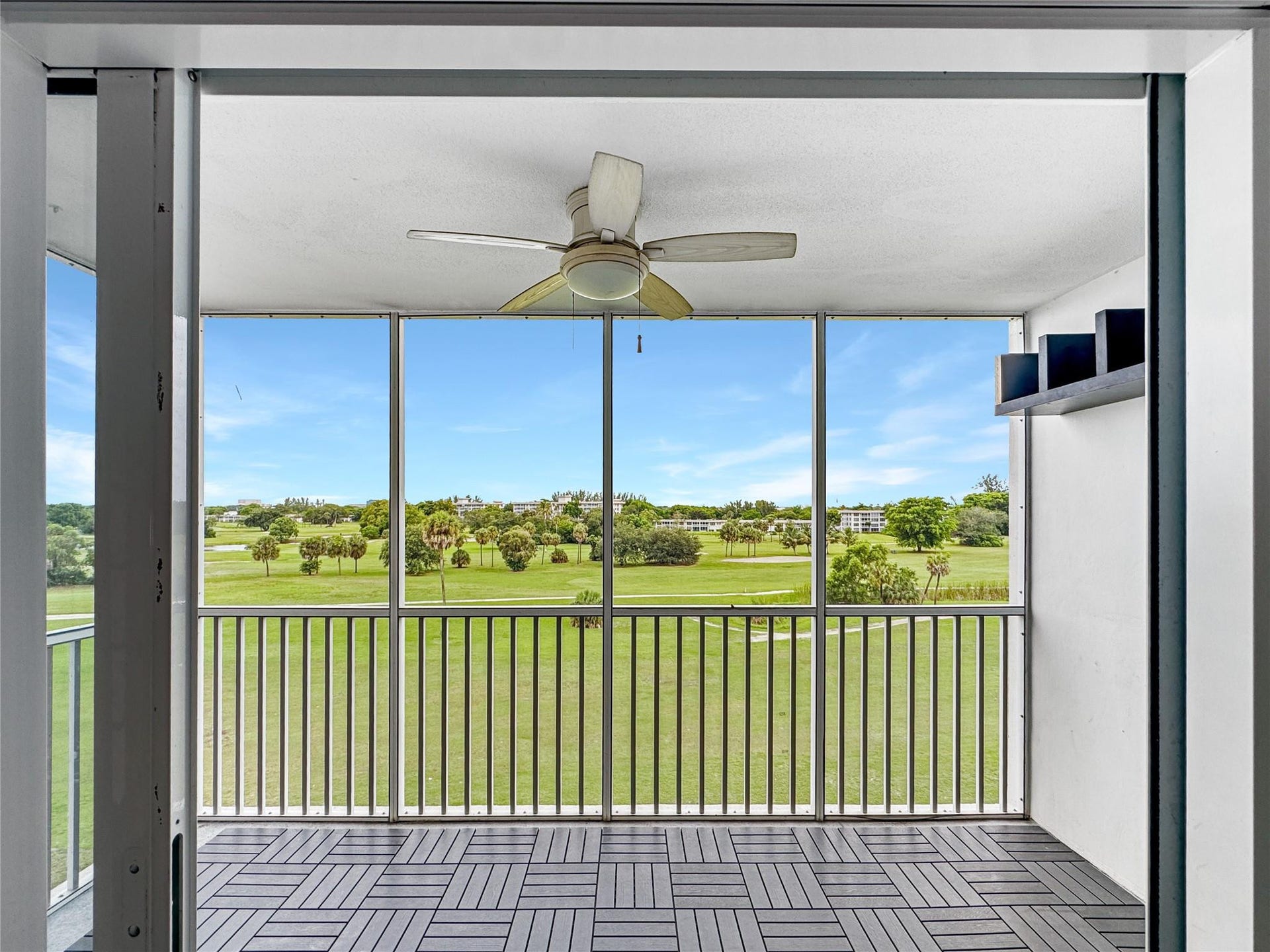 2950 N Palm Aire Drive, #506, Pompano Beach, FL 33069 Screened balcony overlooks wide green space views and offers a comfortable outdoor setting for relaxing or dining. Ceiling fan and tiled flooring enhance the functional outdoor living space.