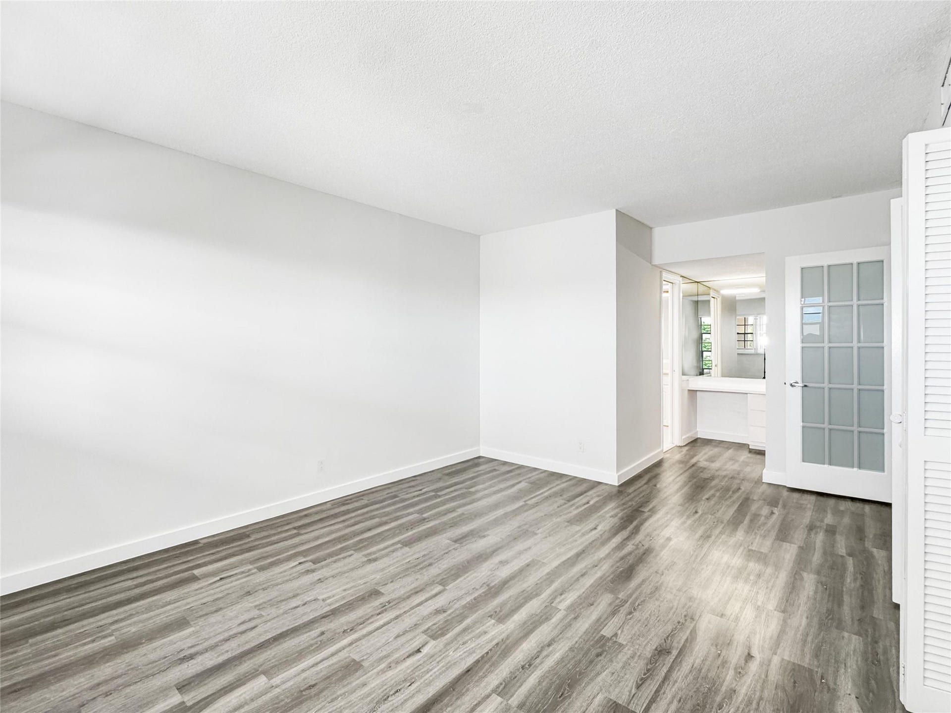2950 N Palm Aire Drive, #506, Pompano Beach, FL 33069 Bedroom features vinyl flooring, neutral walls, and an open layout with access to the adjoining vanity and dressing area. Large closet space provides additional functionality.