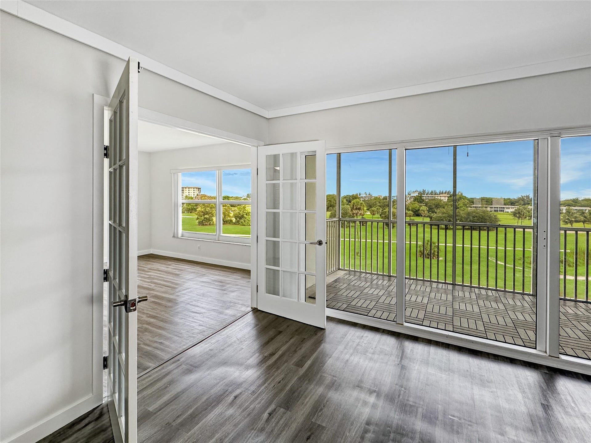 2950 N Palm Aire Drive, #506, Pompano Beach, FL 33069 French doors and expansive sliding glass doors create a seamless connection between the living area and screened balcony, while wide golf course views bring in abundant natural light.