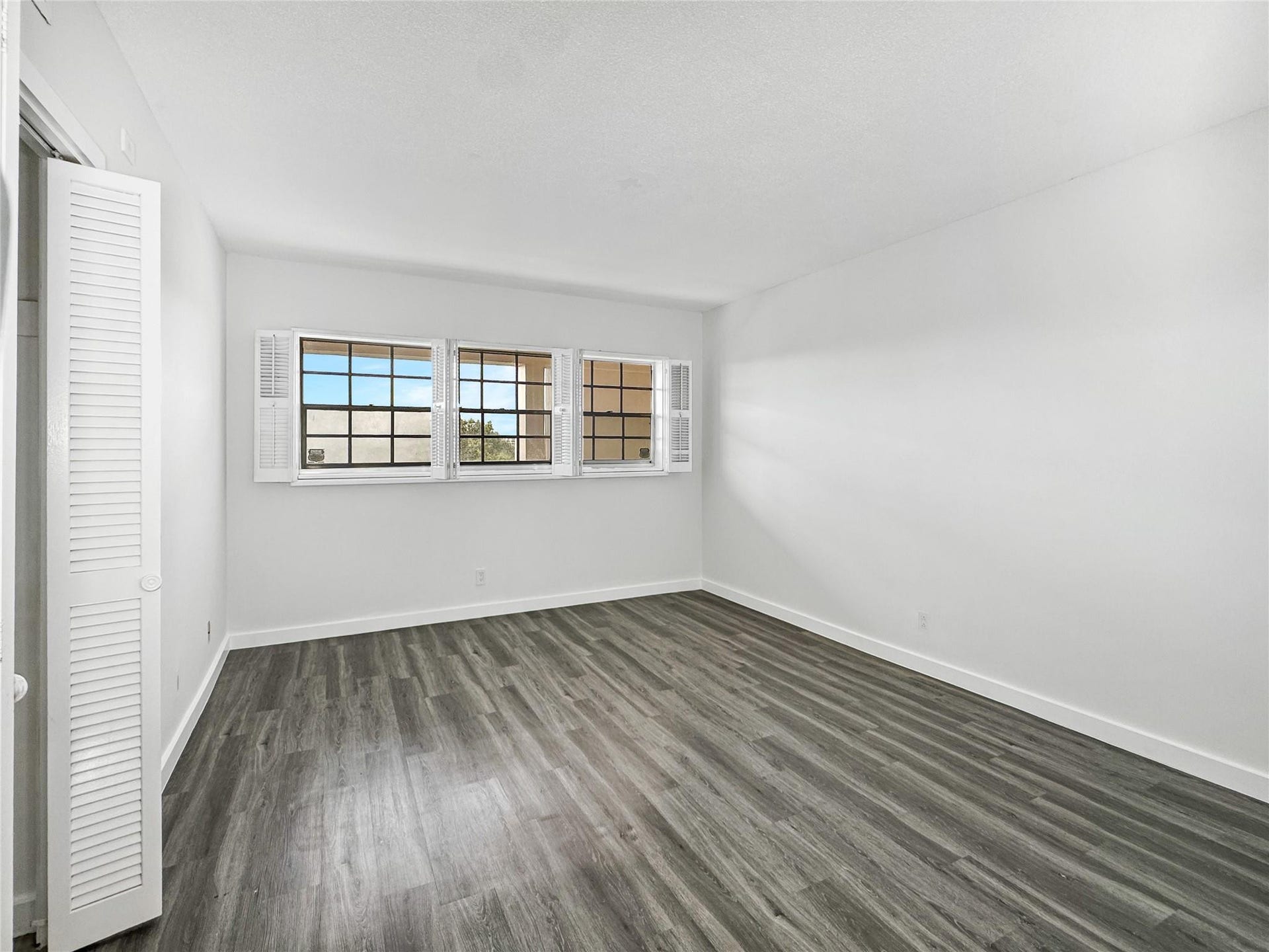 2950 N Palm Aire Drive, #506, Pompano Beach, FL 33069 Bedroom features vinyl flooring, neutral walls, and multiple windows that bring in natural light. The spacious layout offers flexibility for a variety of furniture arrangements.