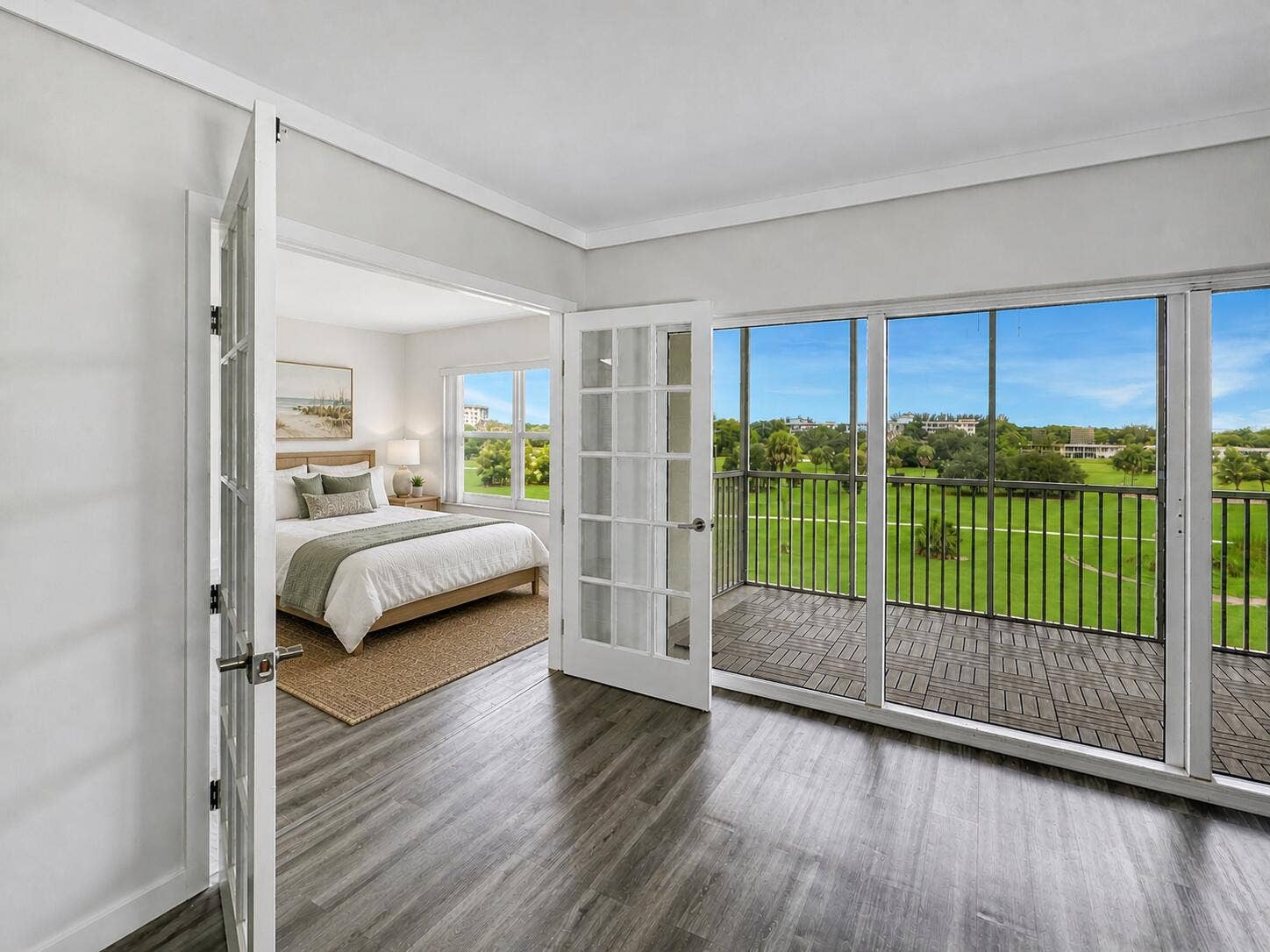 2950 N Palm Aire Drive, #506, Pompano Beach, FL 33069 Second Bedroom features French doors opening directly to the living area, creating flexible use for guests, a home office, or additional living space. Vinyl flooring and large windows provide a bright, airy feel with scenic green space views nearby. Photo has been virtually staged for illustrative purposes. Furniture and decor shown are digitally added.