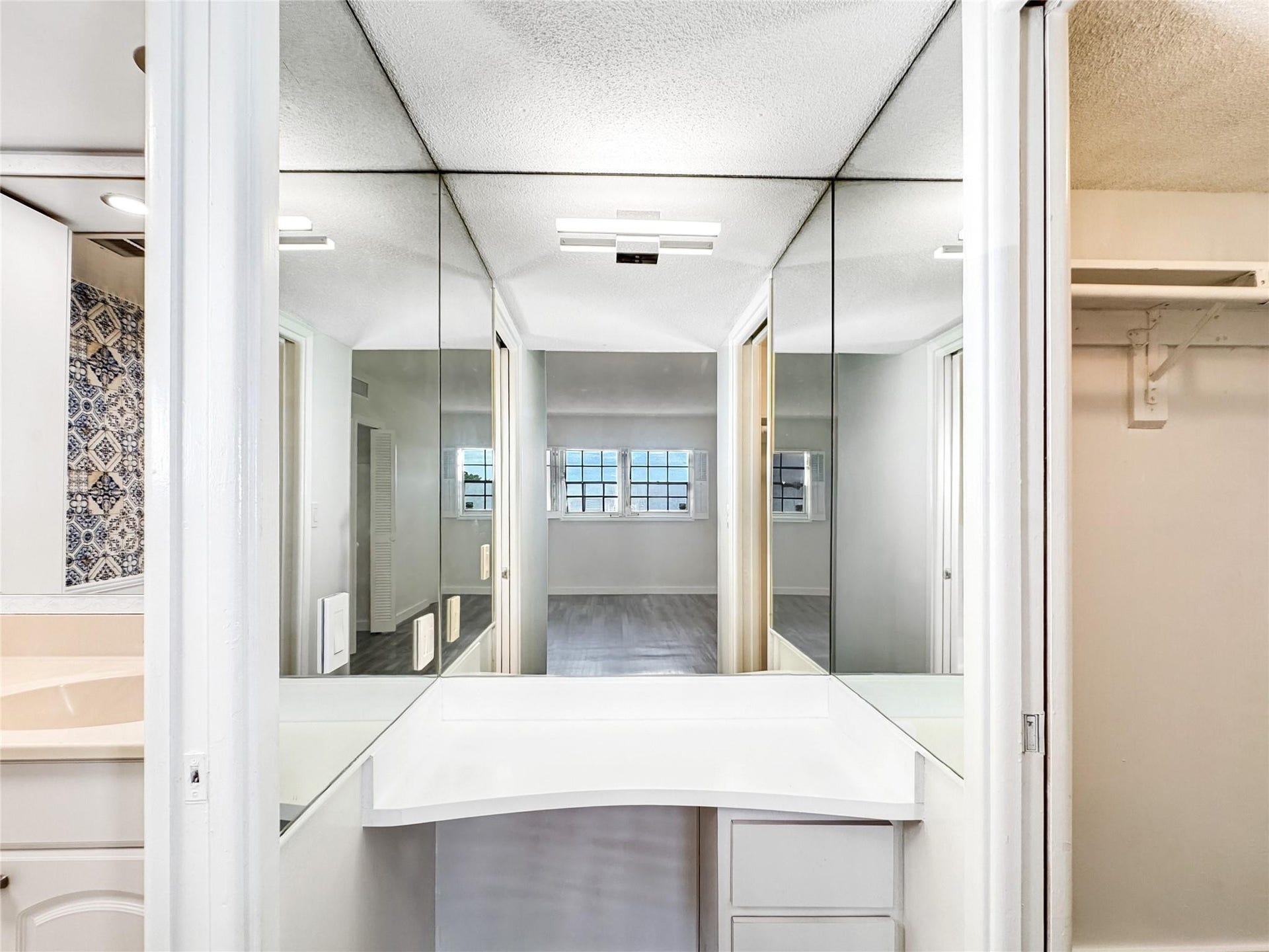 2950 N Palm Aire Drive, #506, Pompano Beach, FL 33069 Vanity area features mirrored walls, built-in counter space, and drawer storage for added functionality. Bright lighting enhances the open feel of the space.