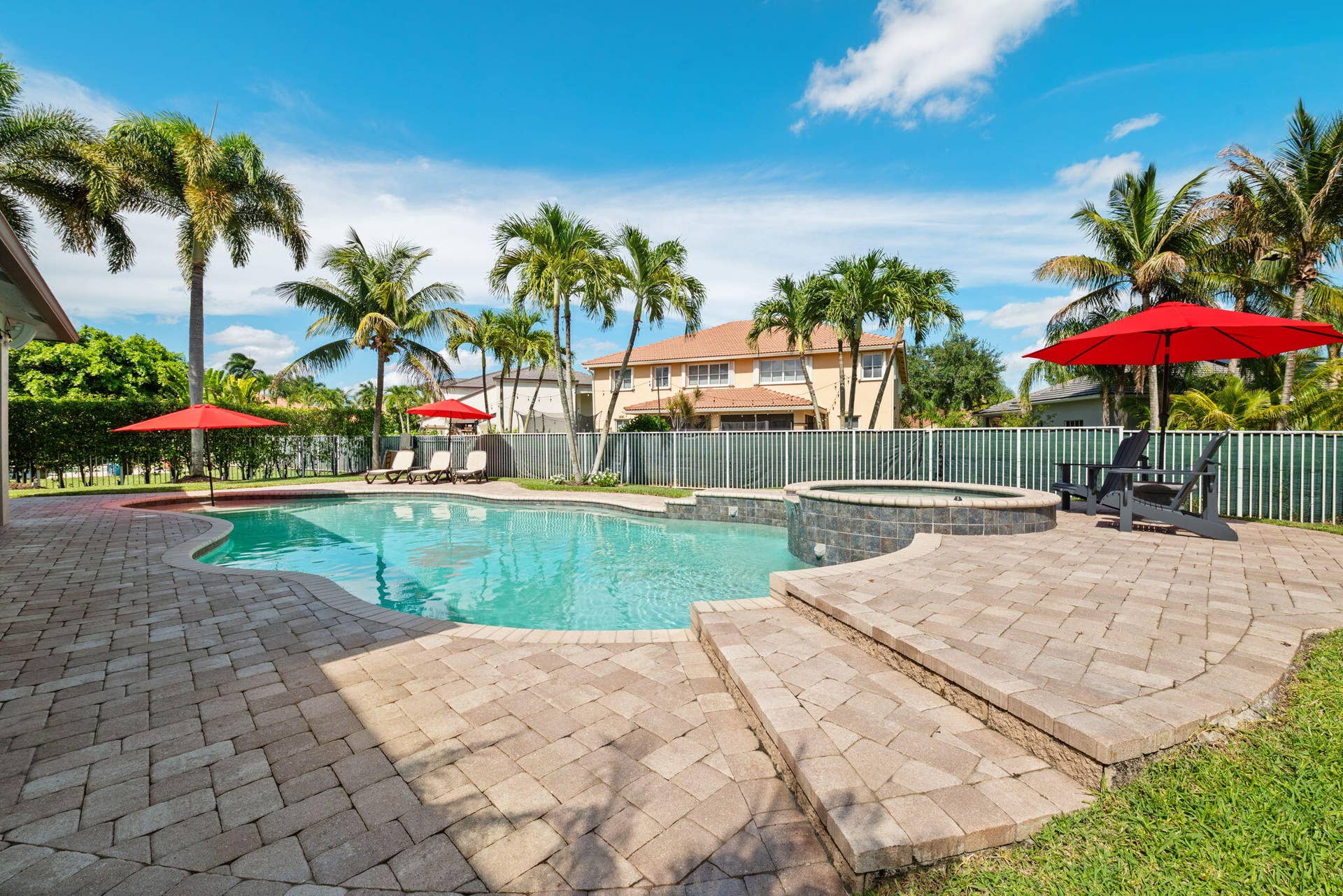 Freeform heated pool and elevated overflow spa surrounded by paver patio.