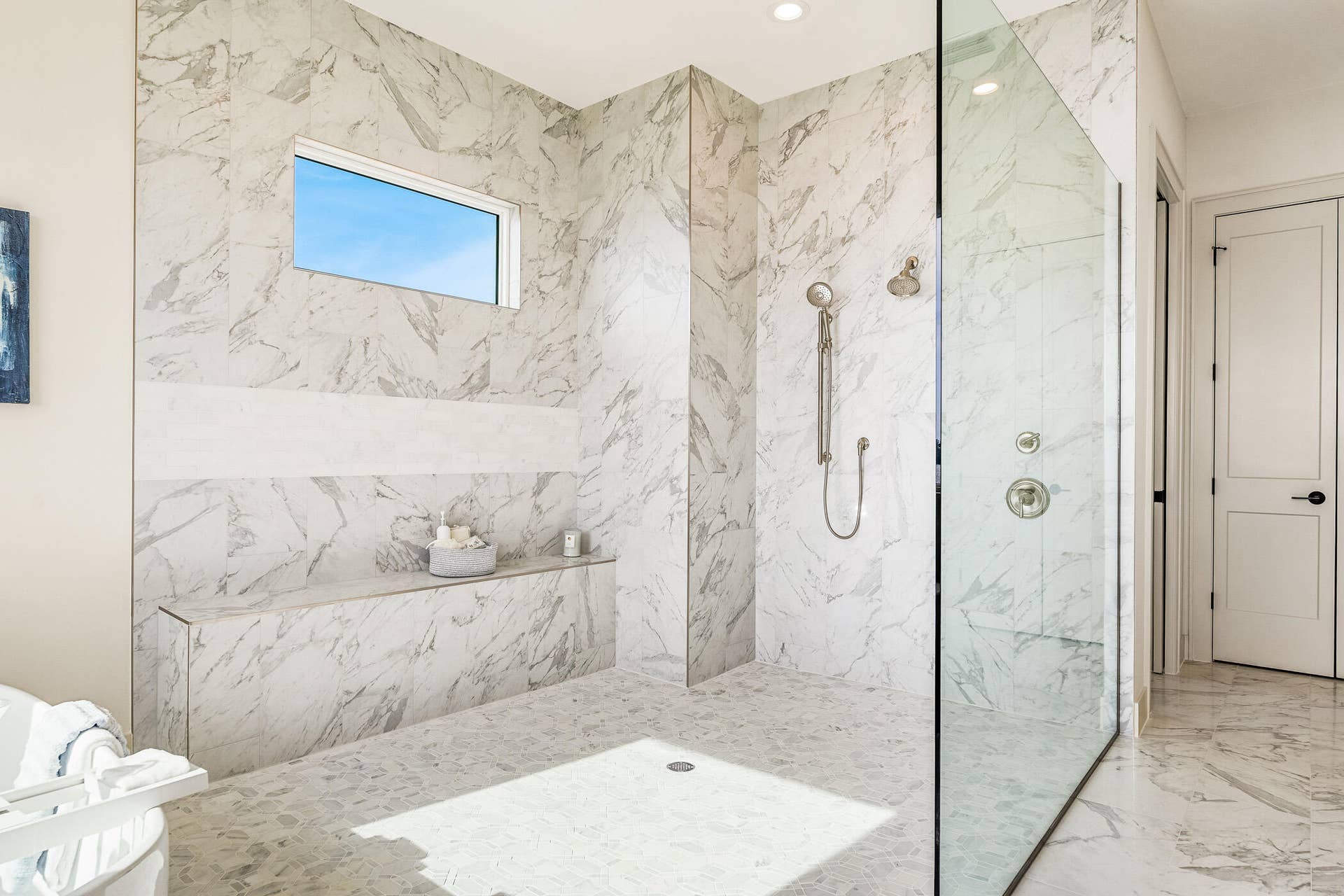 4842 S Harbor Drive, Vero Beach, FL 32967 Meticulously designed walk-in shower showcasing an elongated stone bench and custom glass enclosure.
