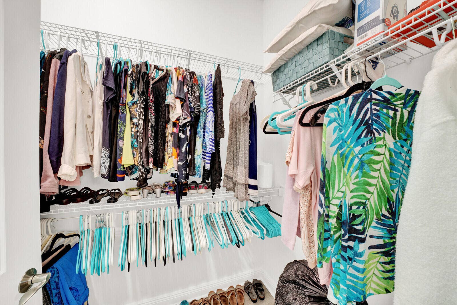 Walk-in closet featuring white wire shelving, multiple hanging rods, and ample storage capacity