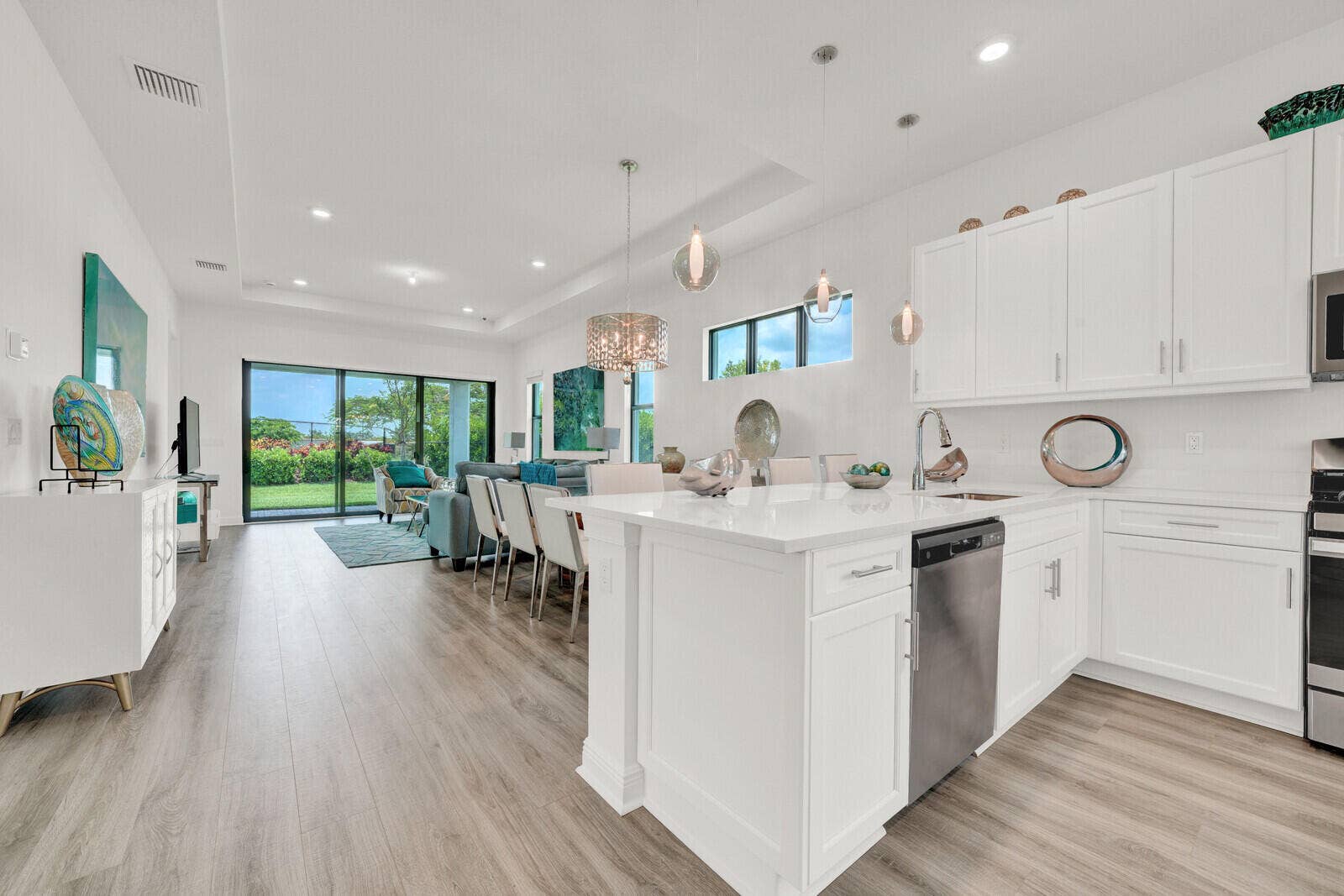 Open-concept living space featuring wood-finish flooring, a contemporary kitchen island with a white countertop, and a full suite of stainless steel appliances