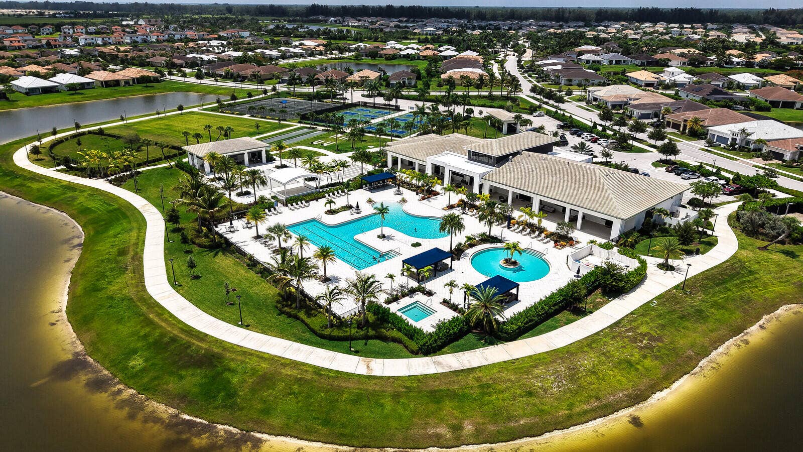 Community clubhouse featuring multiple swimming pools, sports courts, and manicured green spaces