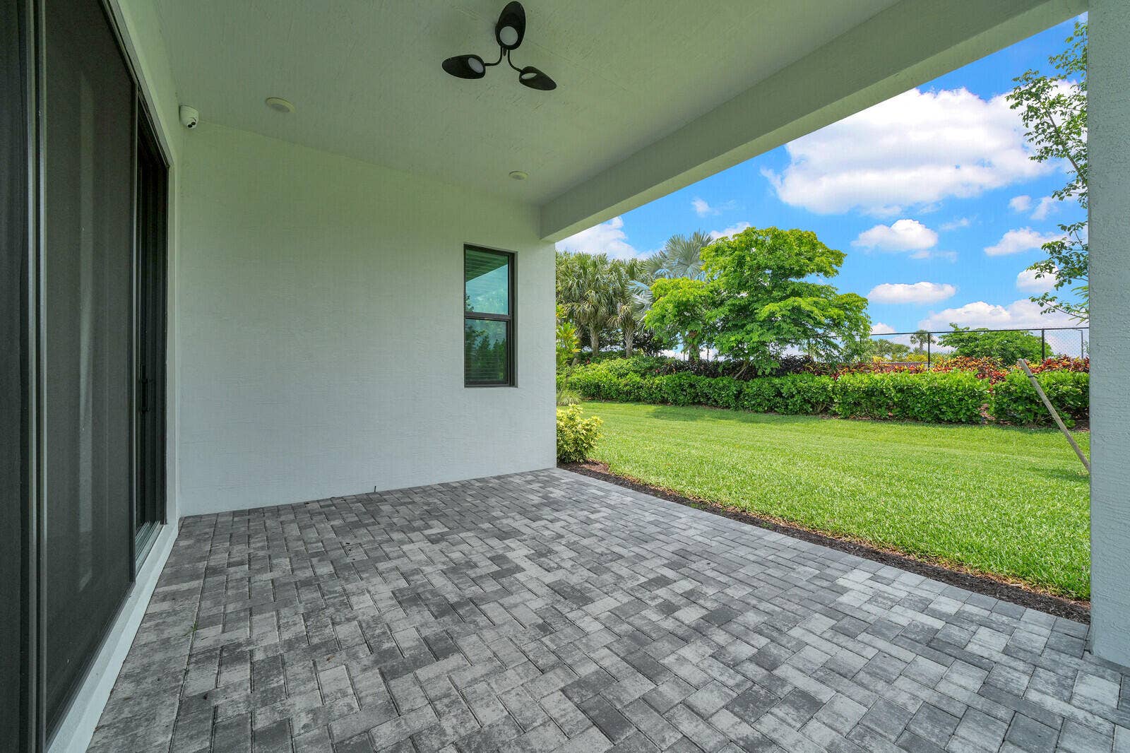 Expansive covered patio featuring patterned paver flooring, a ceiling-mounted fan, and recessed lighting