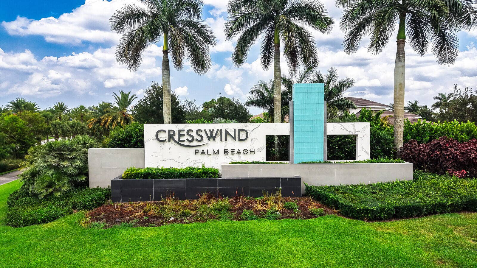 Community entrance signage featuring stone-look panels, embossed lettering, and a tiled accent column