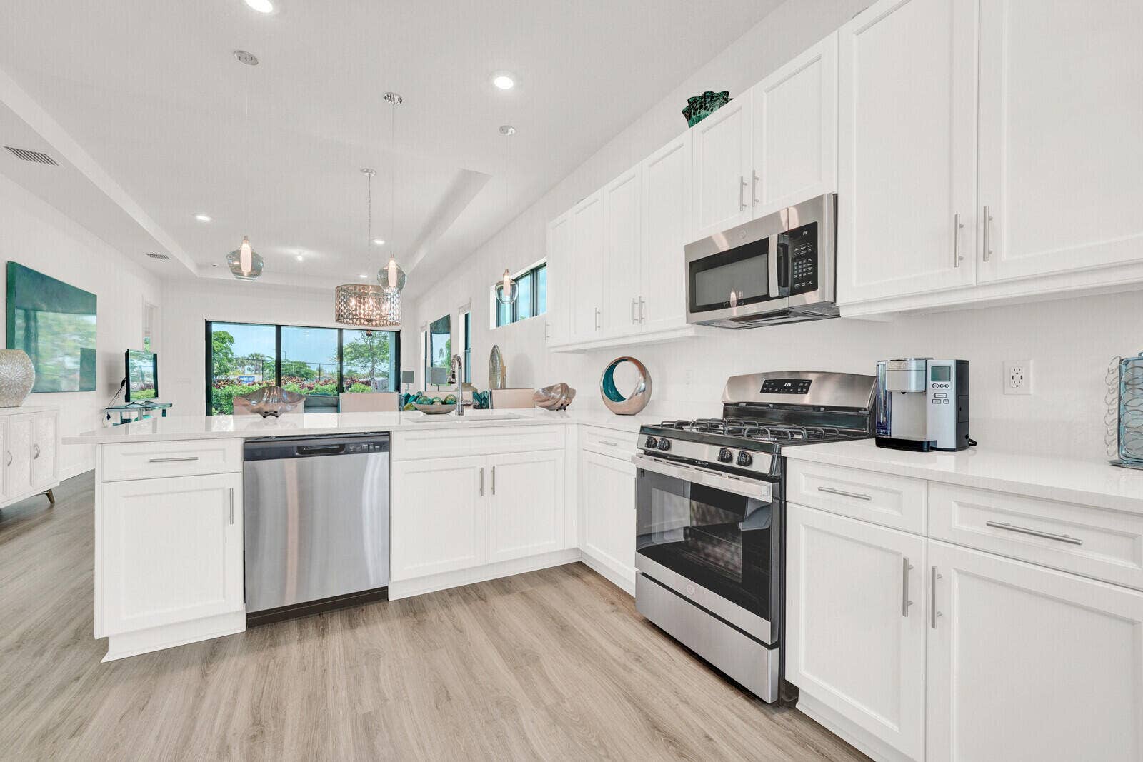 Open-concept kitchen featuring white cabinetry, stainless steel appliances, light-toned wood-finish flooring, and recessed lighting