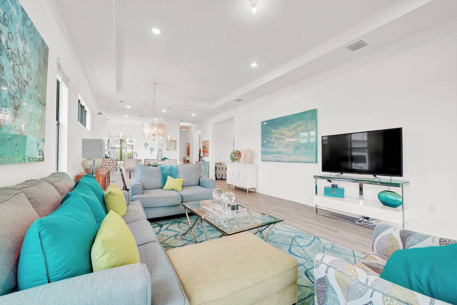 Expansive open-concept living area featuring wood-finish flooring, recessed lighting, and a tray ceiling