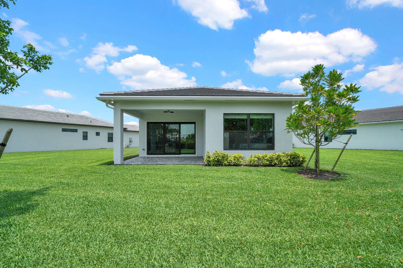 Expansive lawn area featuring a rear covered patio with recessed lighting, ceiling fan, and dark tile flooring