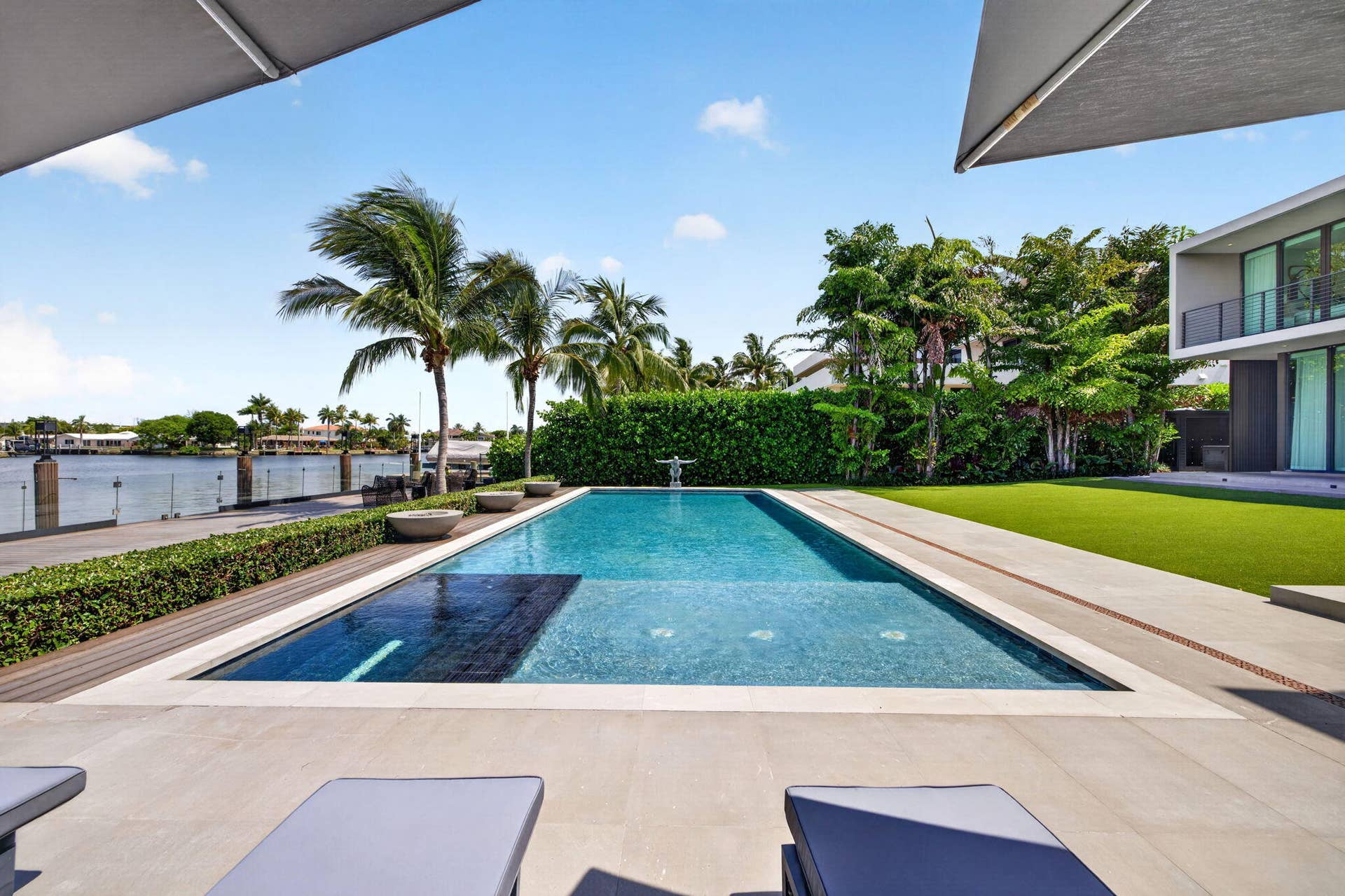 A resort-inspired waterfront setting showcasing the 50-foot saltwater pool, manicured grounds, and striking contemporary rear elevation.