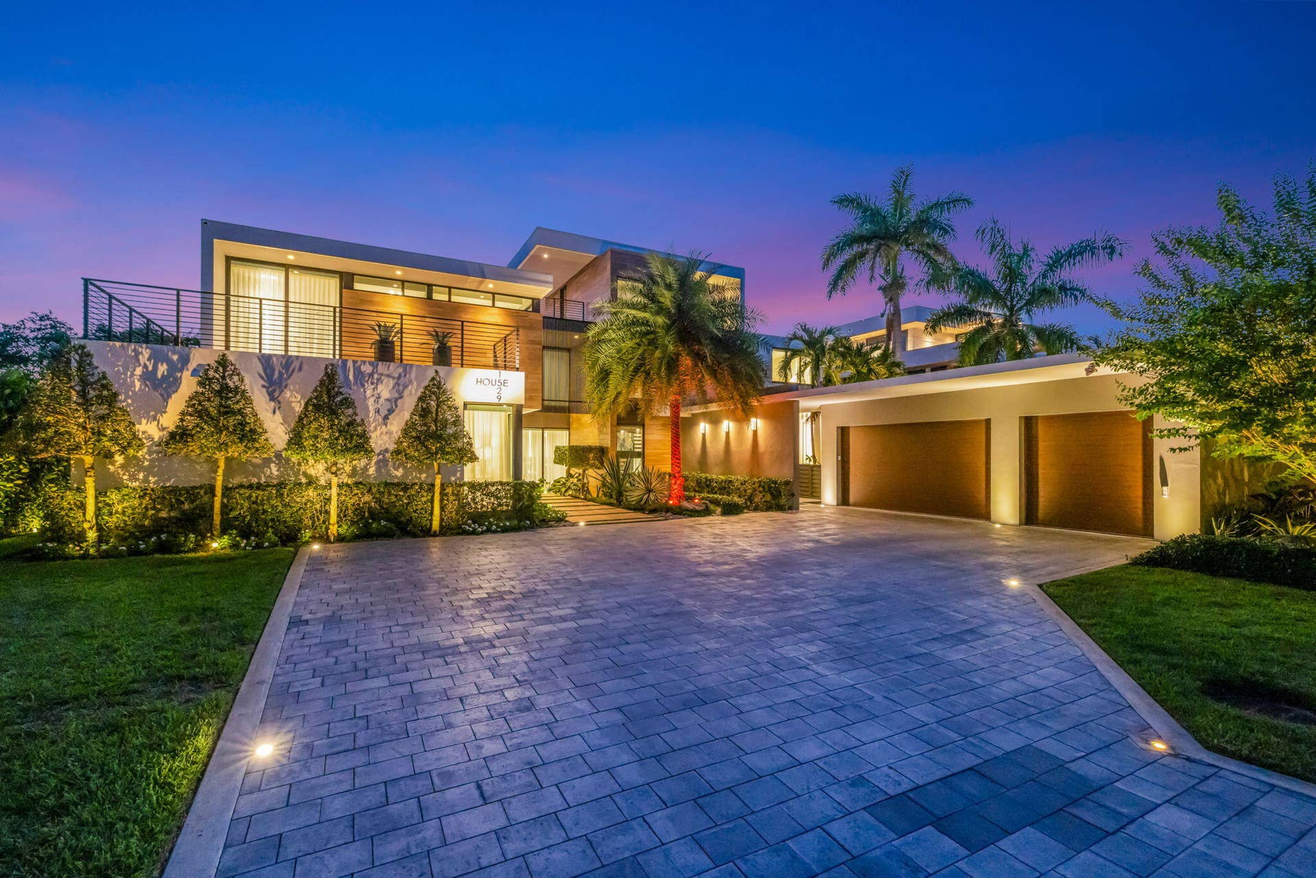 A polished arrival moment showcasing the estates contemporary architecture, private gated setting, tropical landscaping, and impressive motor court presence.