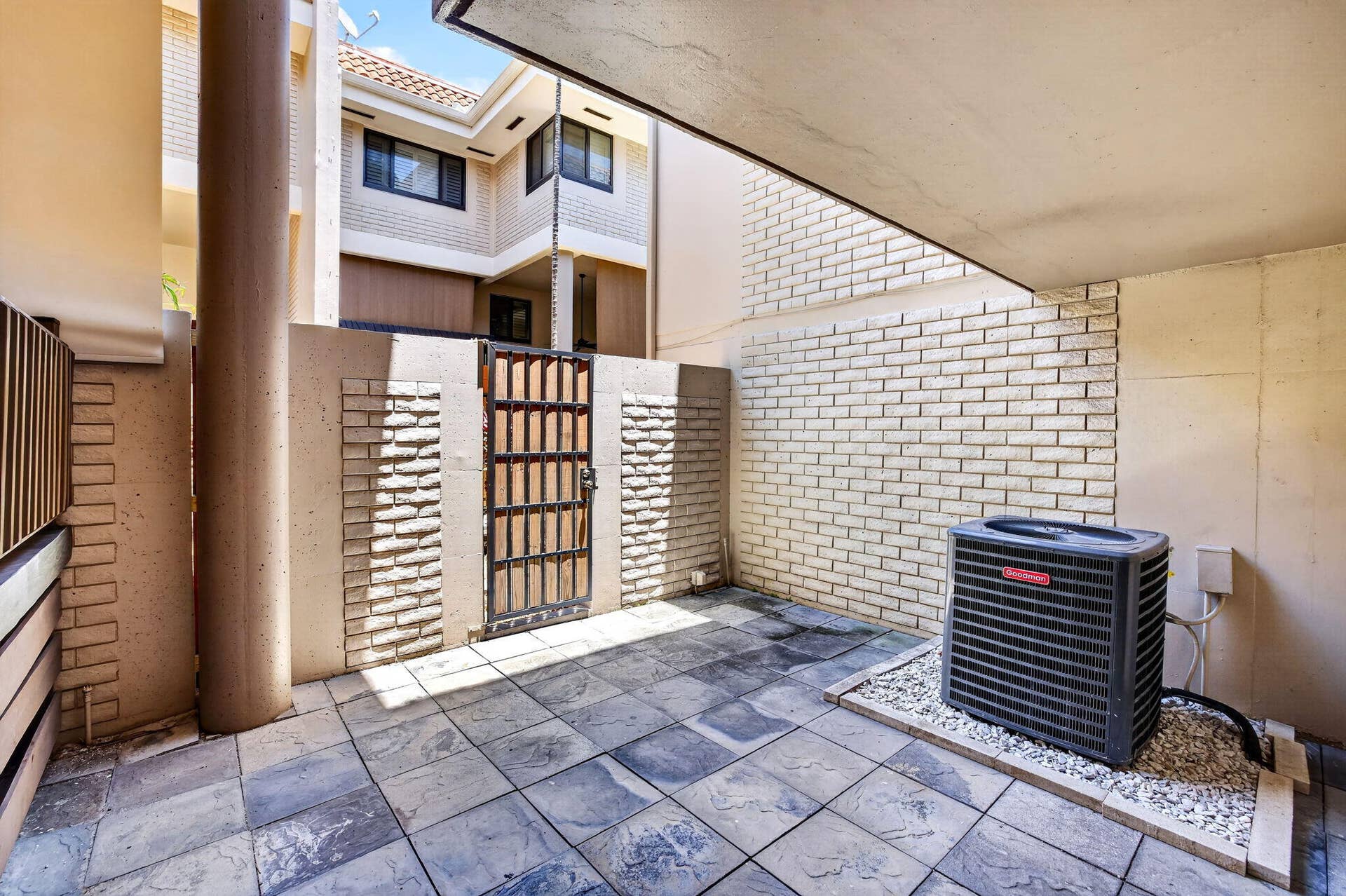 Patio area with access to elevated deck area, garage, and gate to community pool