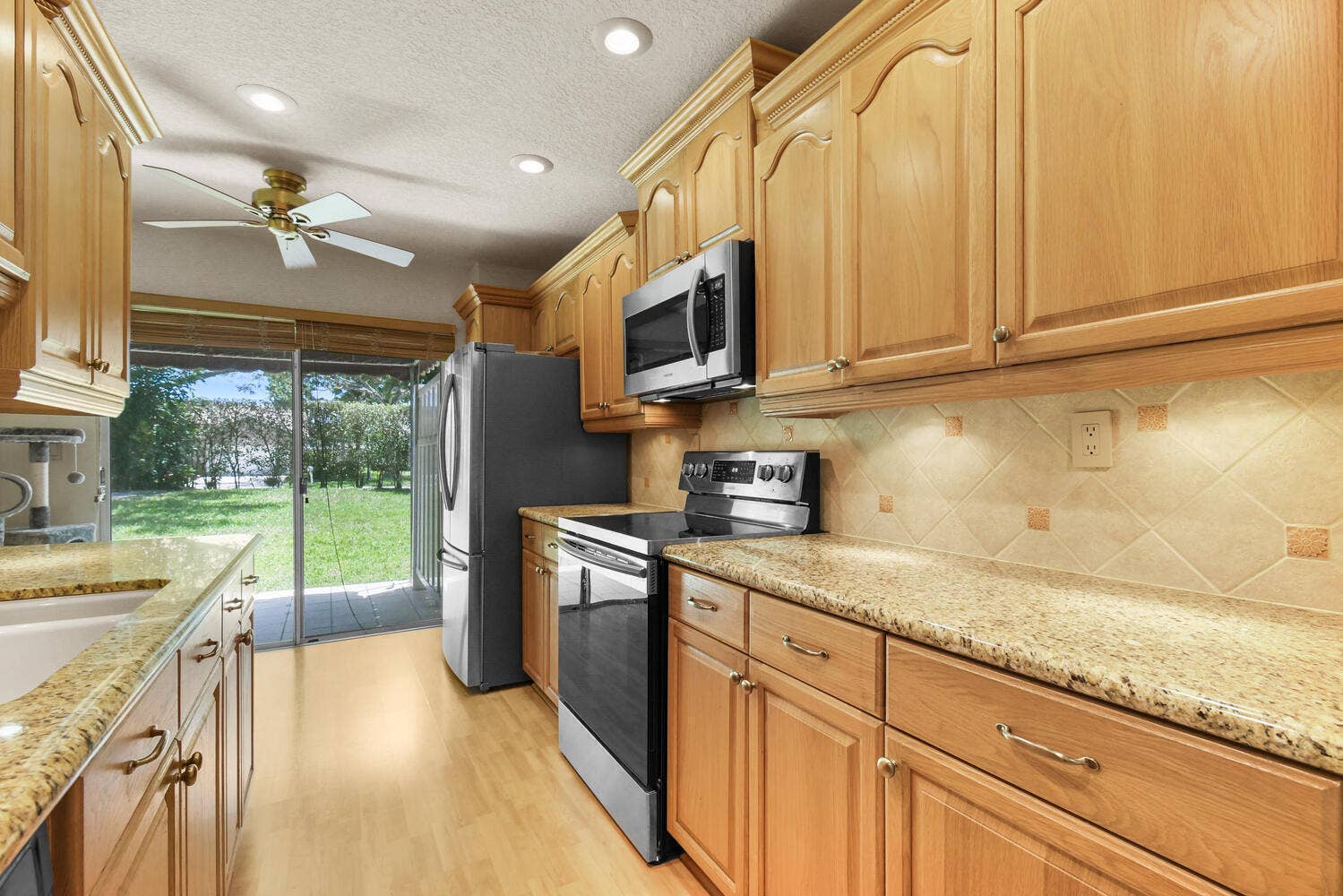 5266 Sapphire Valley, Boca Raton, FL 33486 Beautifully updated kitchen featuring granite countertops, abundant cabinetry, stainless steel appliances, recessed lighting, and direct access to the patio, creating a bright and functional space for everyday living.